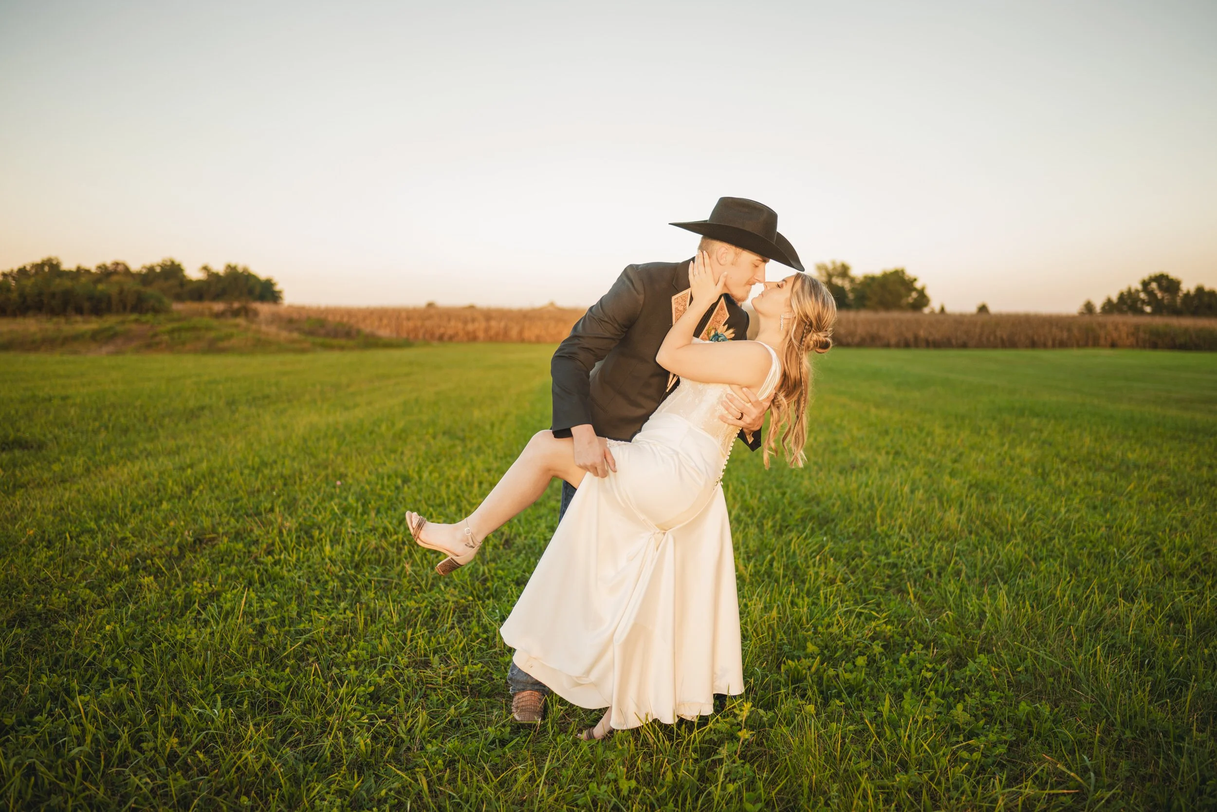 A groom dips his bride at sunset on an Indiana farm.