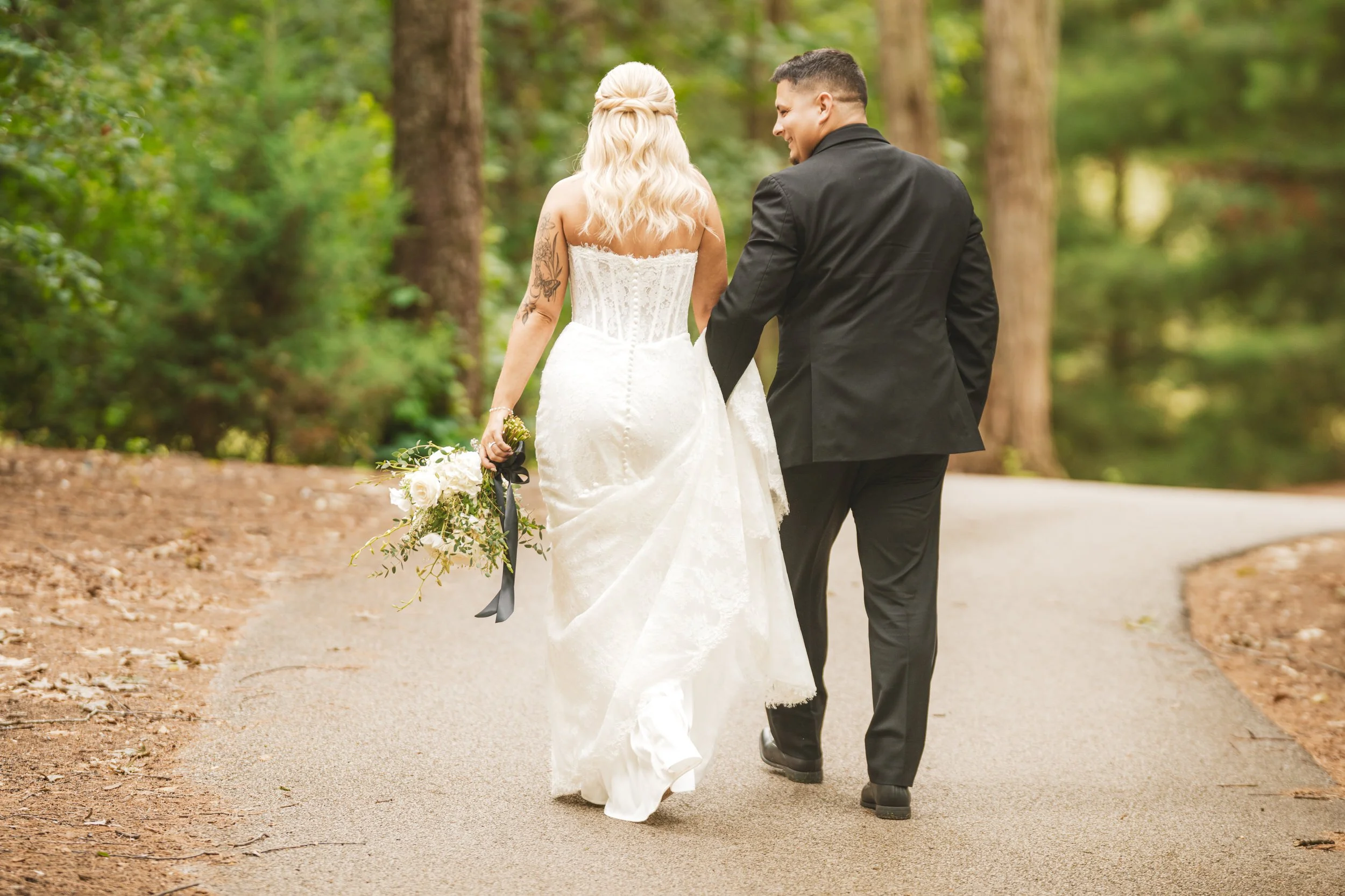 A bride and groom take a stroll in the woods at Sandy Pines golf course in Demotte, IN.