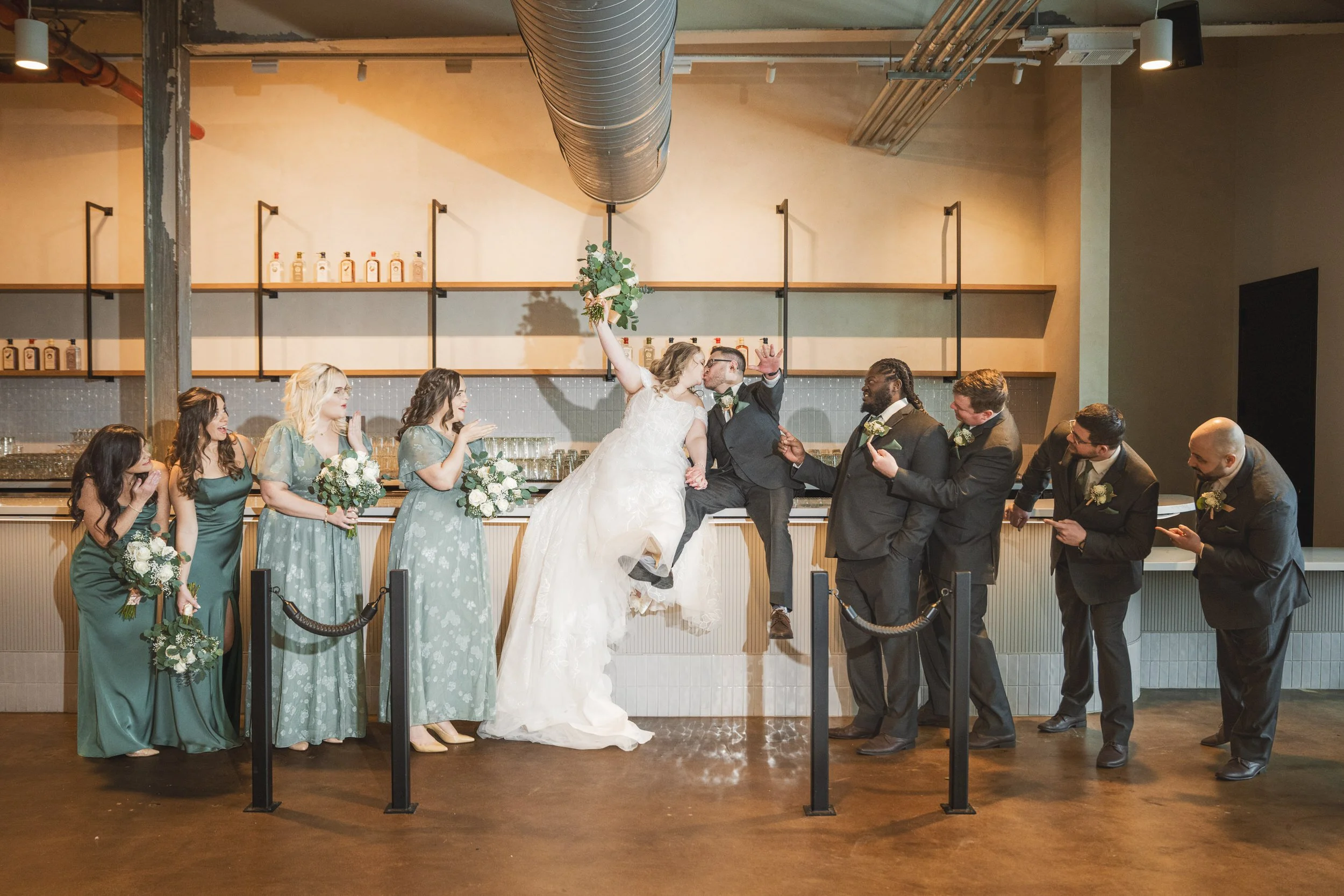 The wedding party celebrates on top of the bar at Journeyman Distillery.