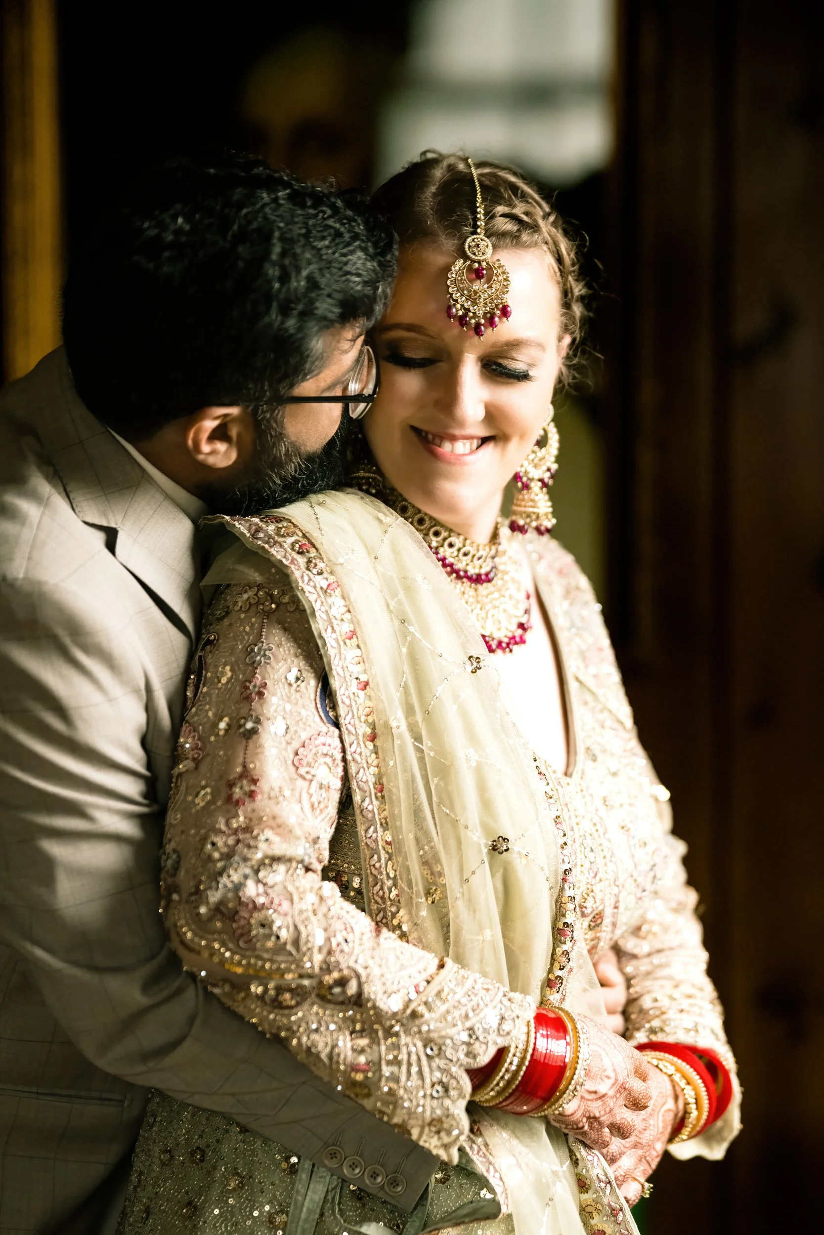 An intimate moment as the Indian groom embraces his bride from behind.