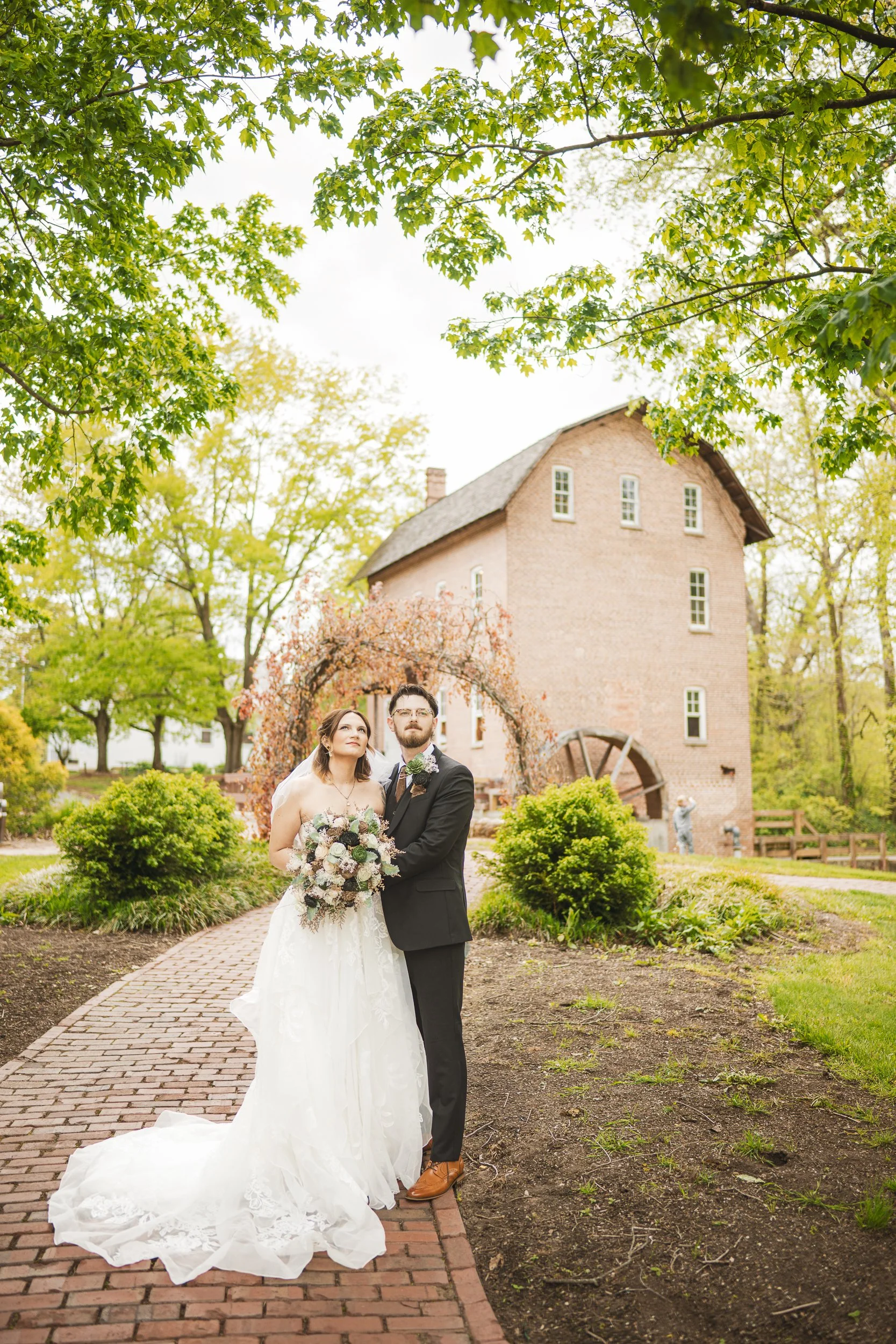 A bride and and groom look off in the distance while standing on a cobble stgone path at Deep River County Park in Merrillville, Indiana.
