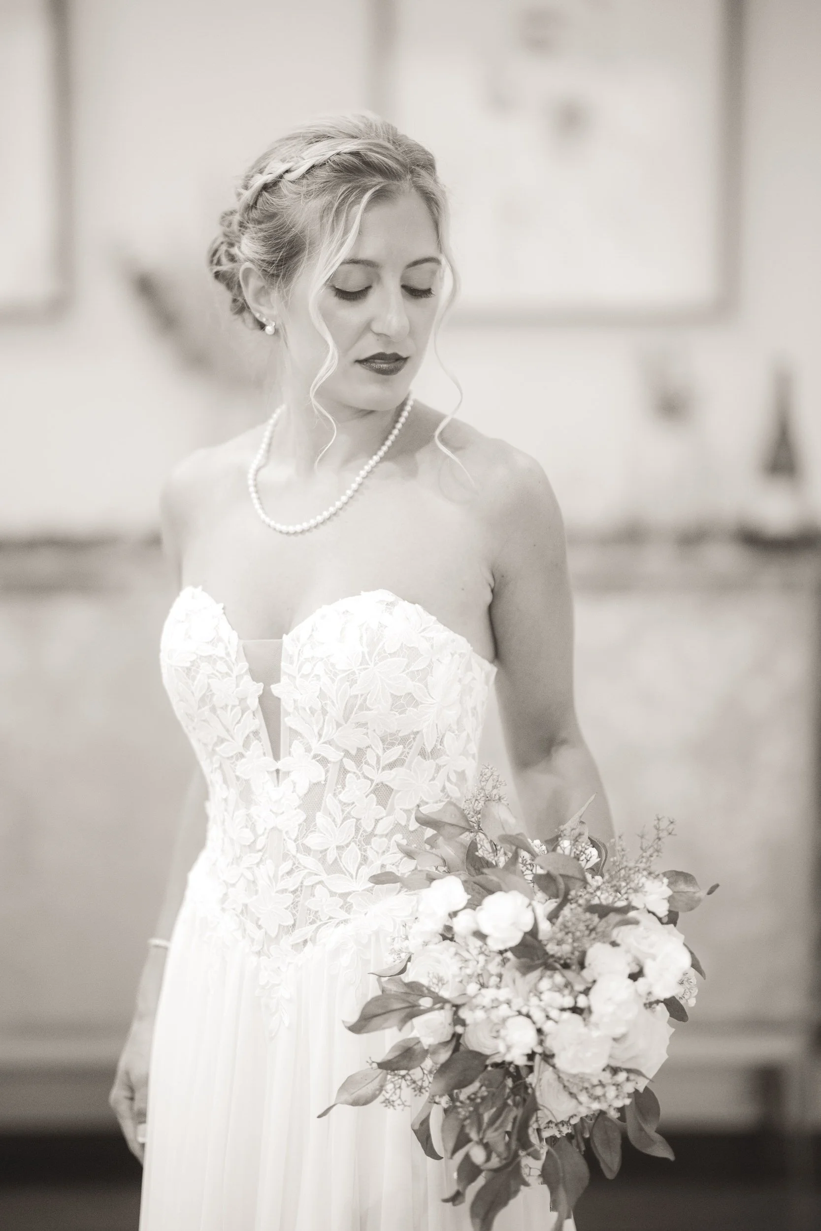 A bride looks down her shoulder to her bouquet of flowers in this wedding photo at White Oak Farm Venue.