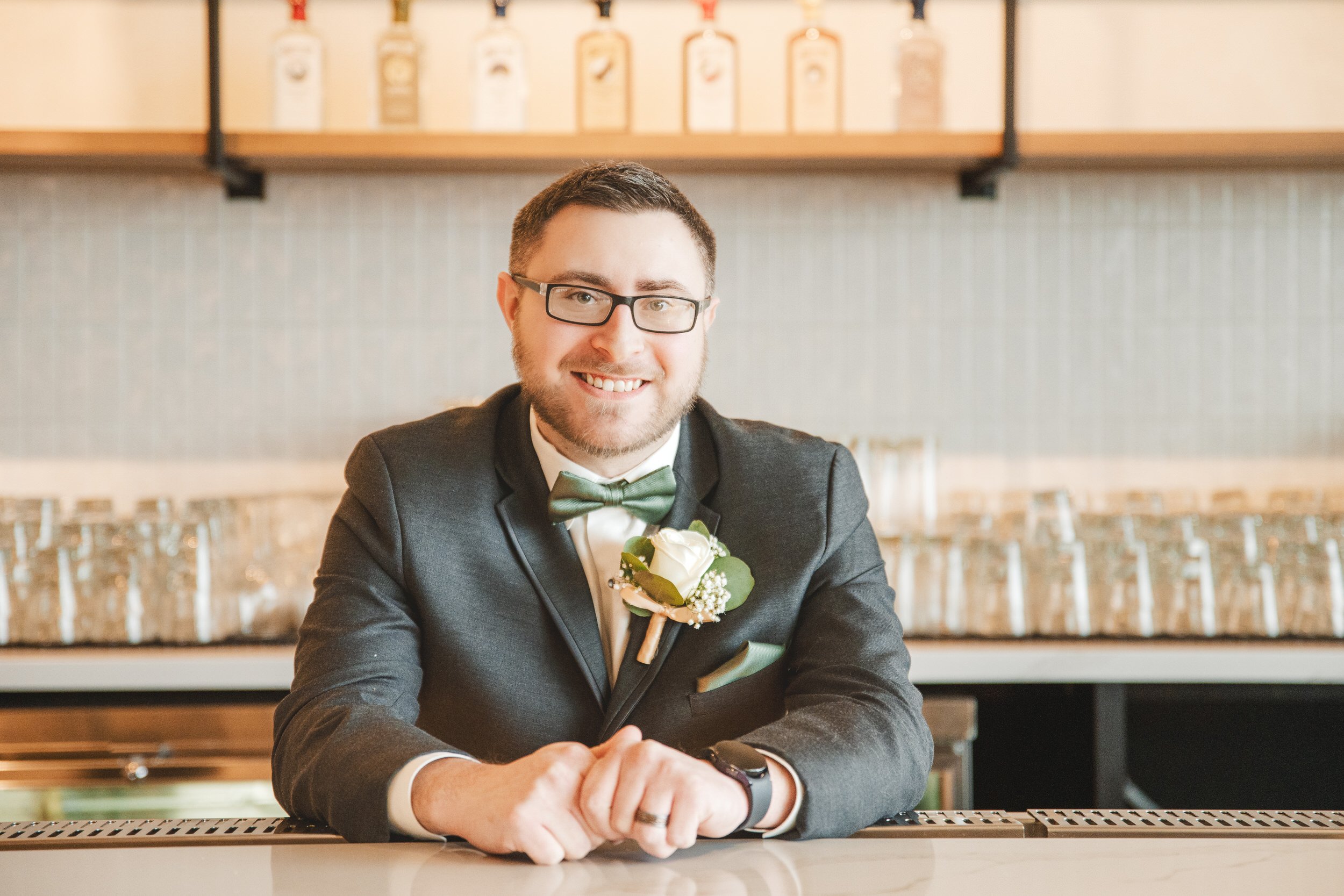 The groom stands behind the bar at Journeyman Distillery.