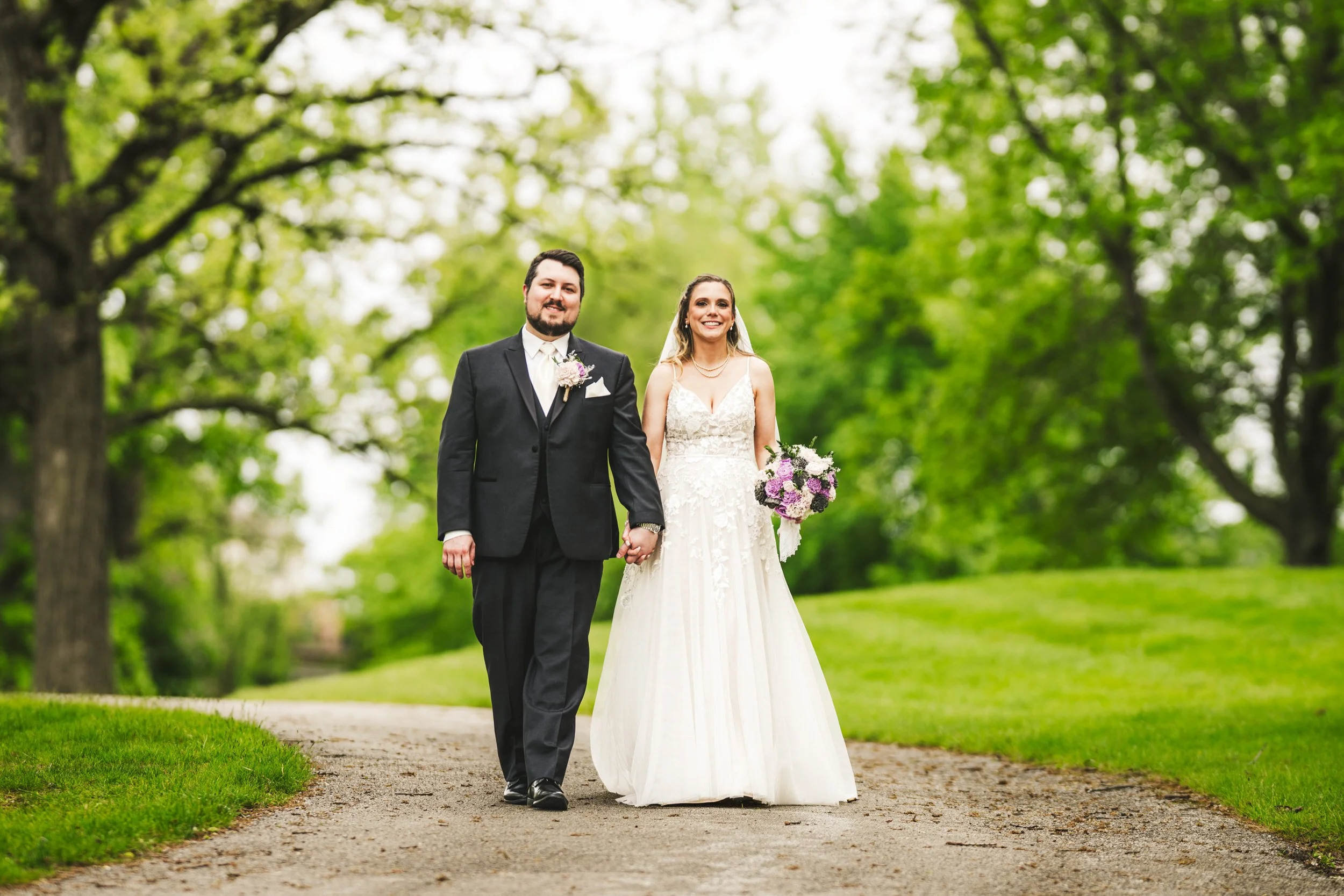 A newly married bride and groom take a walk down a path at Lake Hills Park in St. John, Indiana.