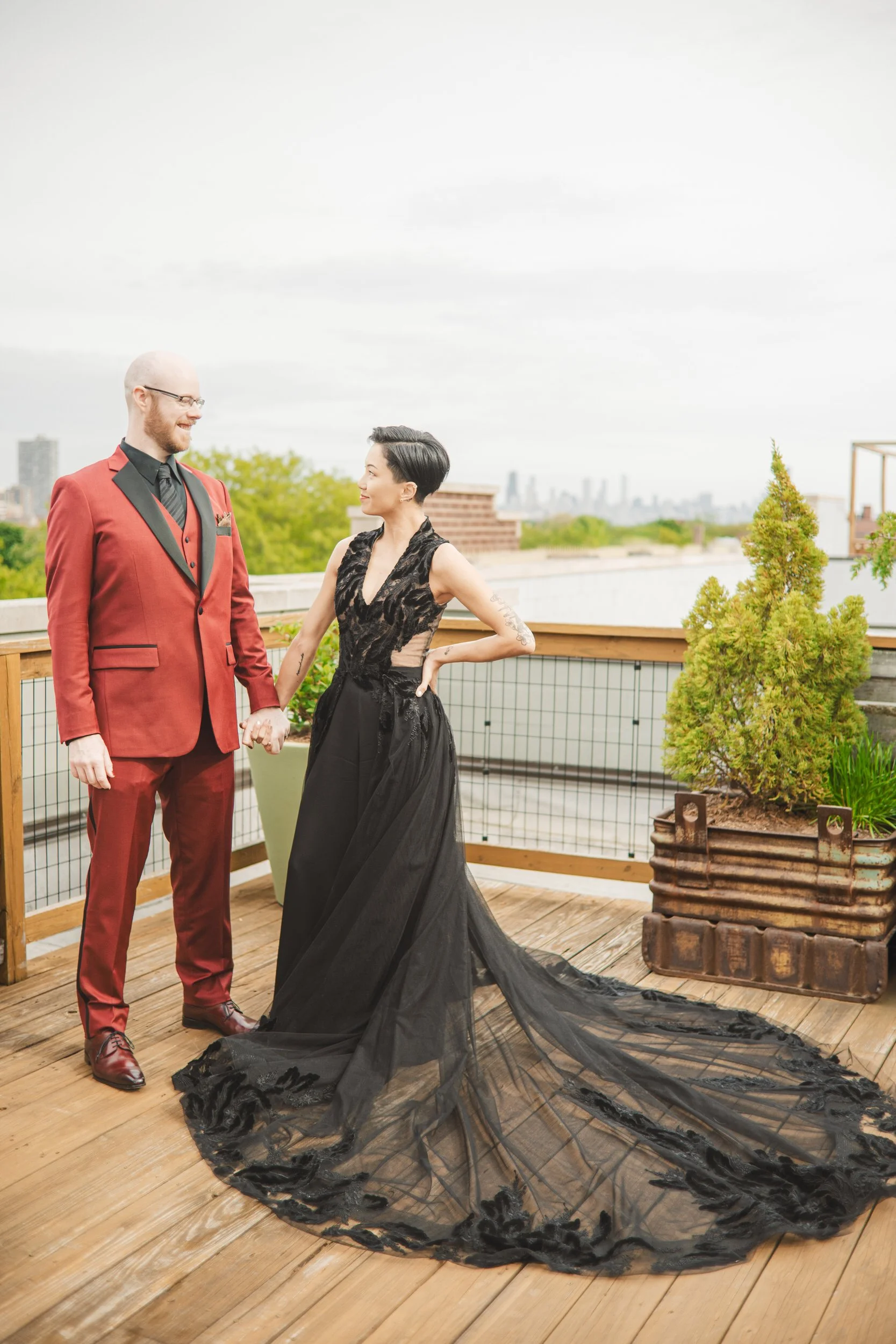 A bride and groom stand on the rooftop of The Guest House Hotel with the Chicago skyline in the background.