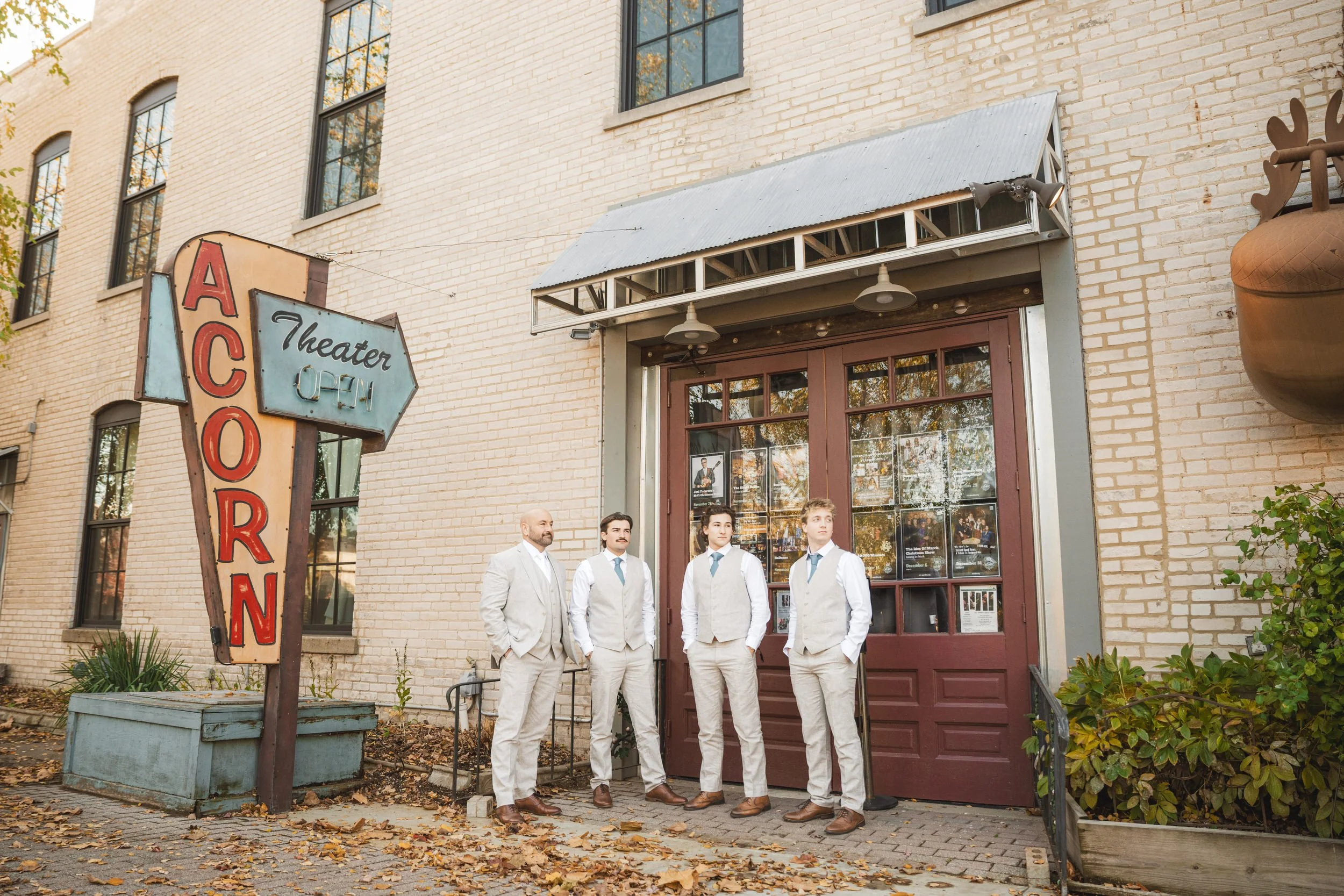 The groom stands outside the Acorn Theater with his ons, the groomsmen at his wedding.