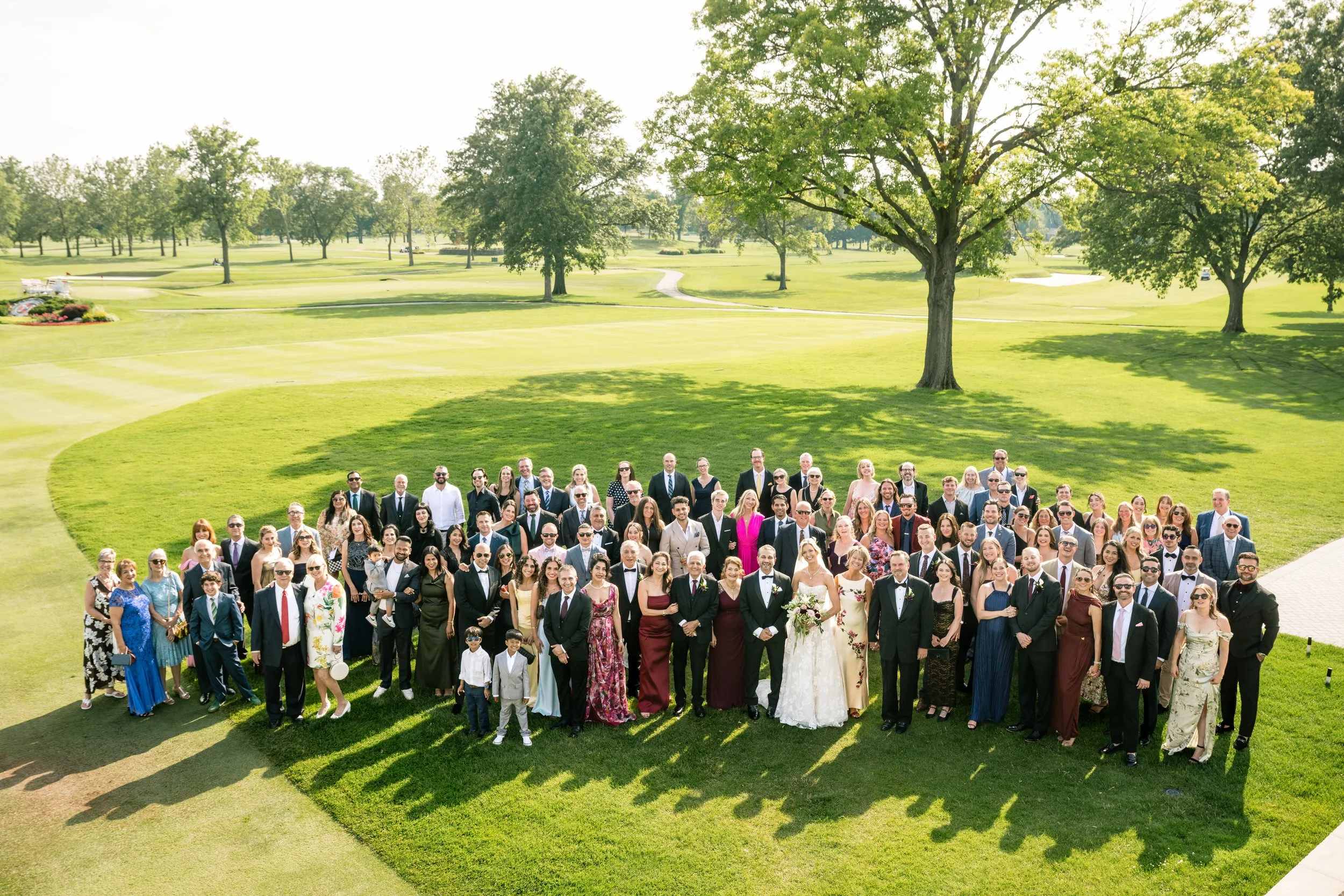 A large group photo shot with all of the wedding guests standing on the green at Midlothian Country Club.