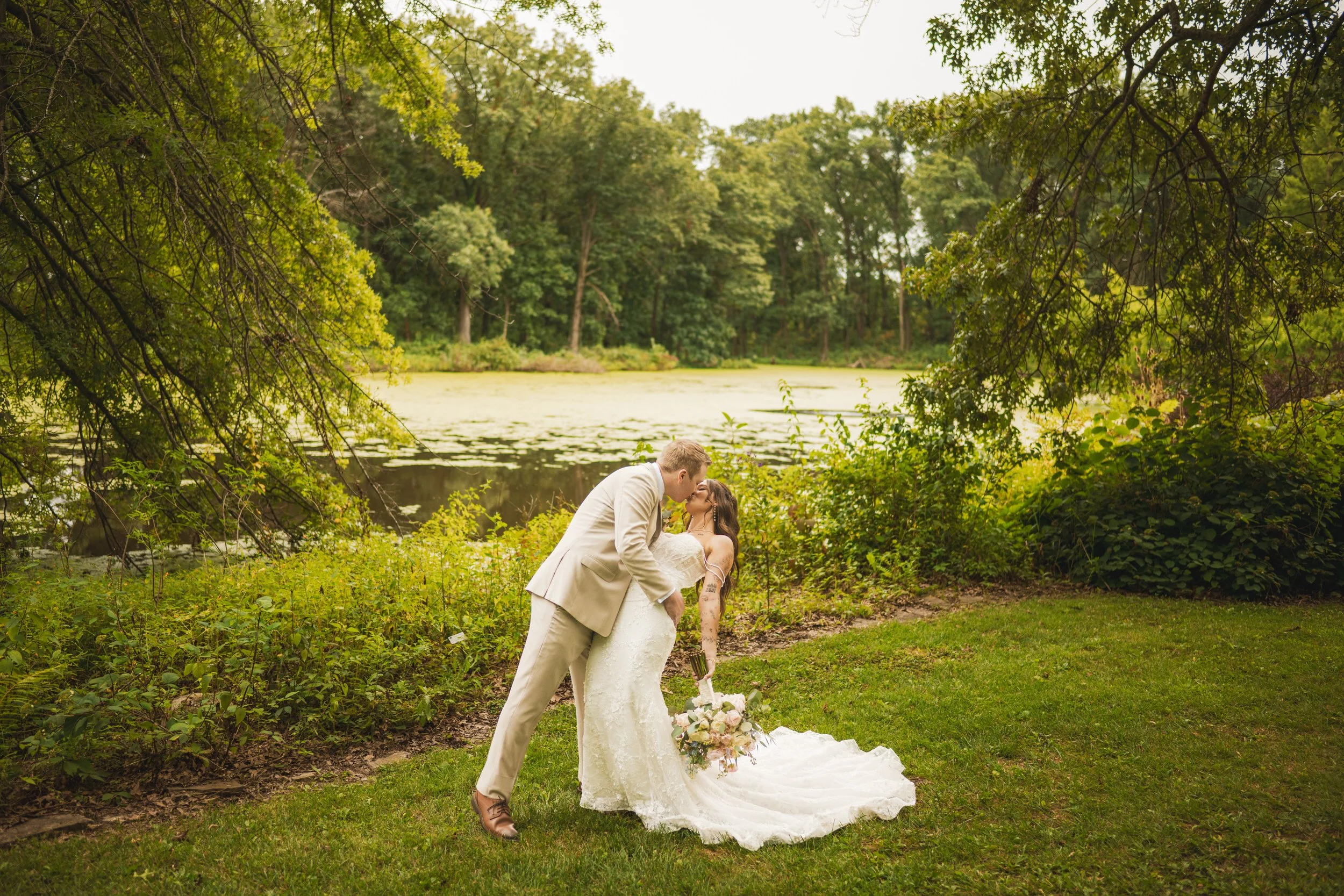 The groom dips his bride with the swampy lake of Gabis Arboretum as the backdrop.
