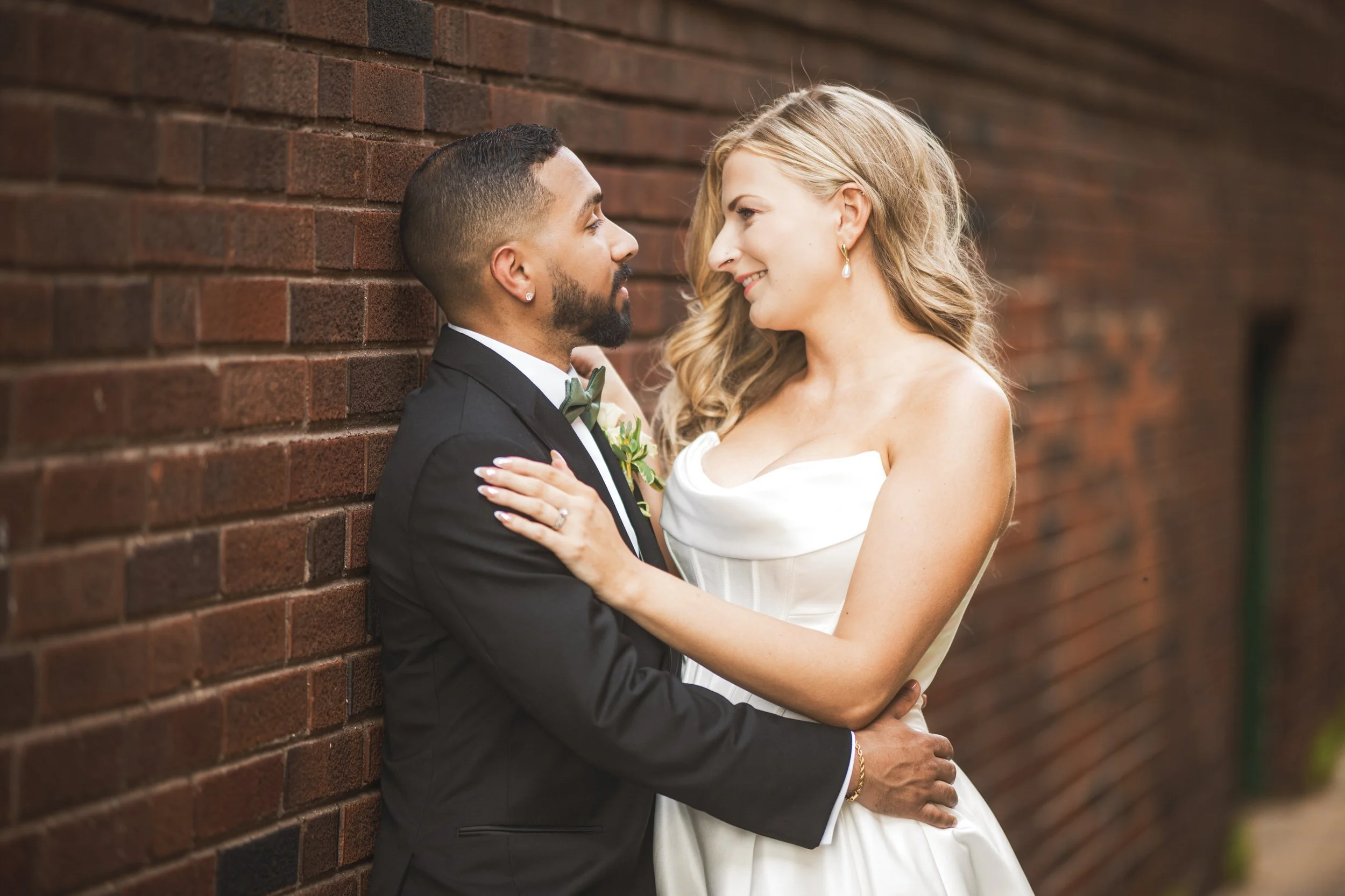 A bride and groom embrace in an alleyway with beautiful red brick in downtown Crown Point, Indiana.