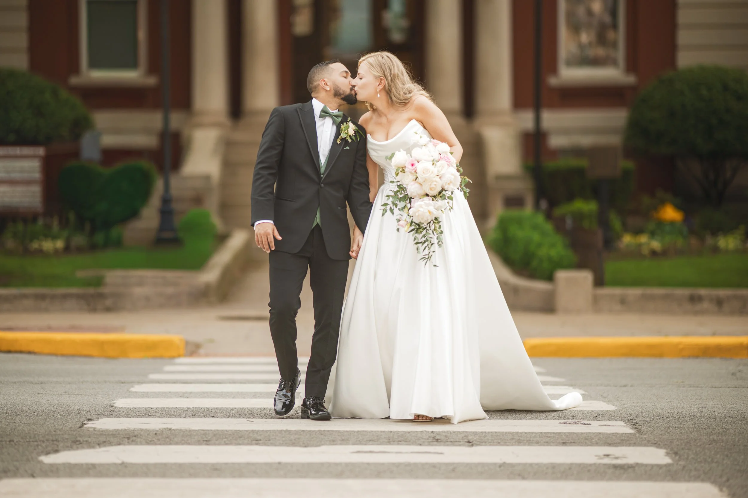 The bride and groom kiss as they cross Main Street in downtown Crown Point, Indiana.