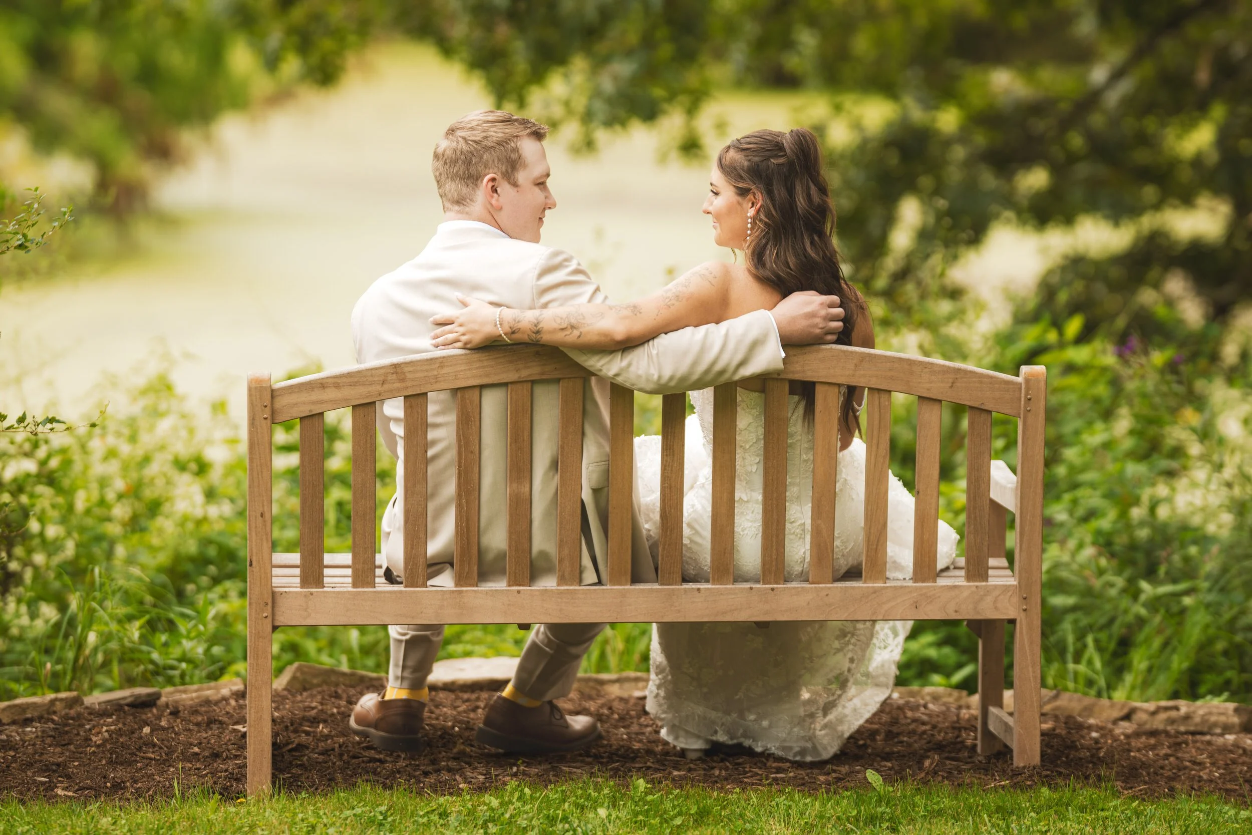 Bride and groom sit on a bench overlooking the lake at Gabis Arboretum in Valparaiso, Indiana.