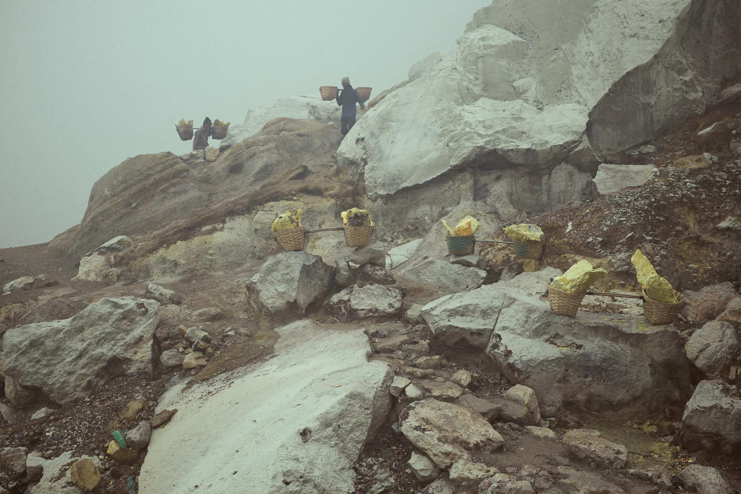 Miners work with three loads shuttling them up the crater in short distances. Paid by the kilo that they transport to the weigh station at the bottom of the mountain. Ijen Crater, Java, Indonesia. Ijen is mined for sulphur. ©Laurence Gibson