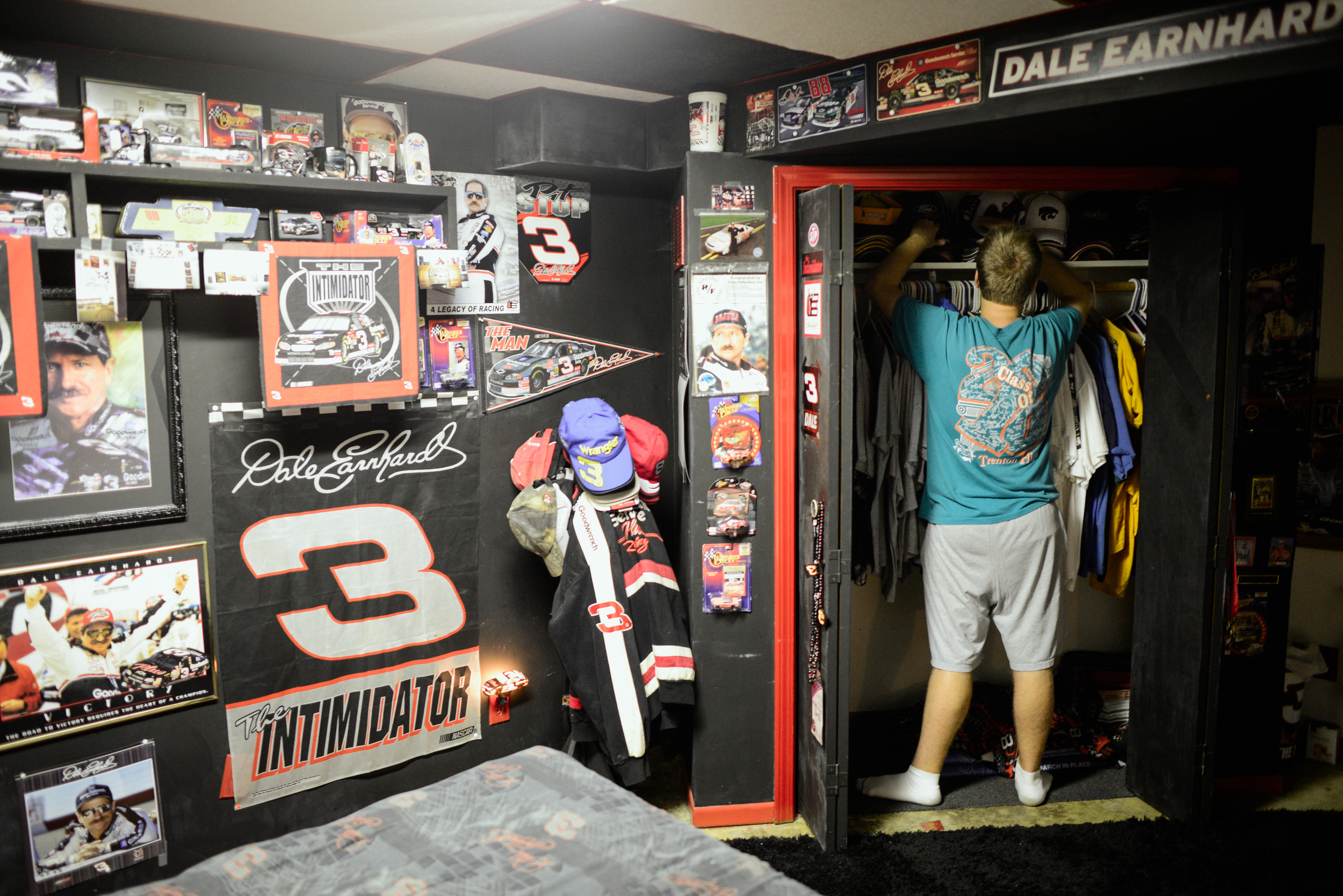  Trenton, Missouri. 2013.  Dalton straightens his hat collection in his bedroom closet. While a fan of many sports his bedroom is dedicated exclusively to Dale Earnhardt. 