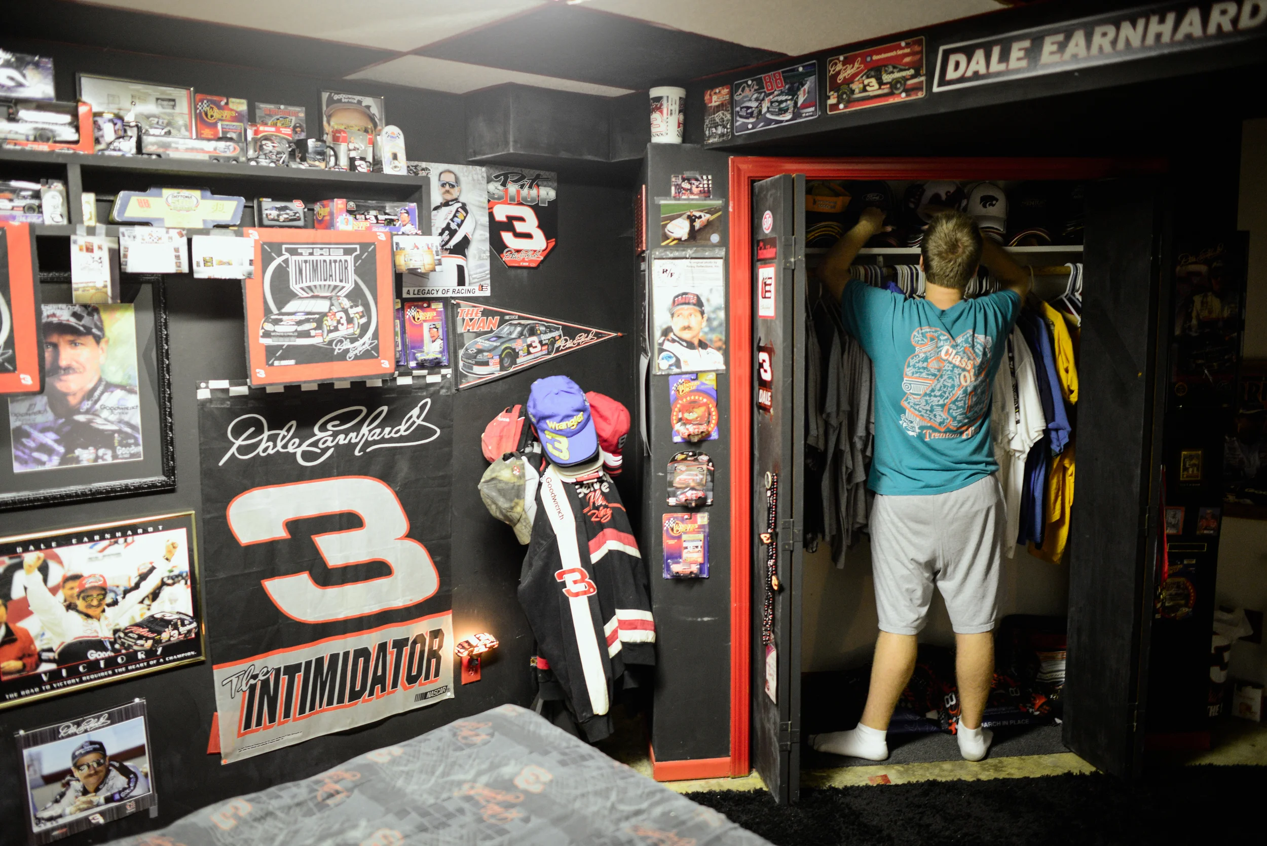 Trenton, Missouri. 2013. Dalton straightens his hat collection in his bedroom closet. While a fan of many sports his bedroom is dedicated exclusively to Dale Earnhardt.