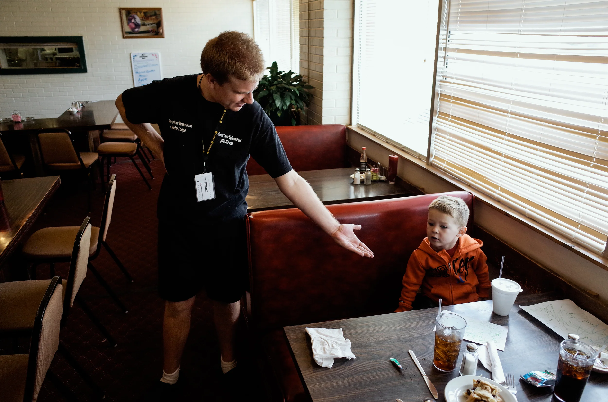Trenton, Missouri. 2013. One day a week Dalton works at the Lakeview Motor Lodge and Restaurant rolling silverware and wiping chairs. He always finds time to share a moment with customers.