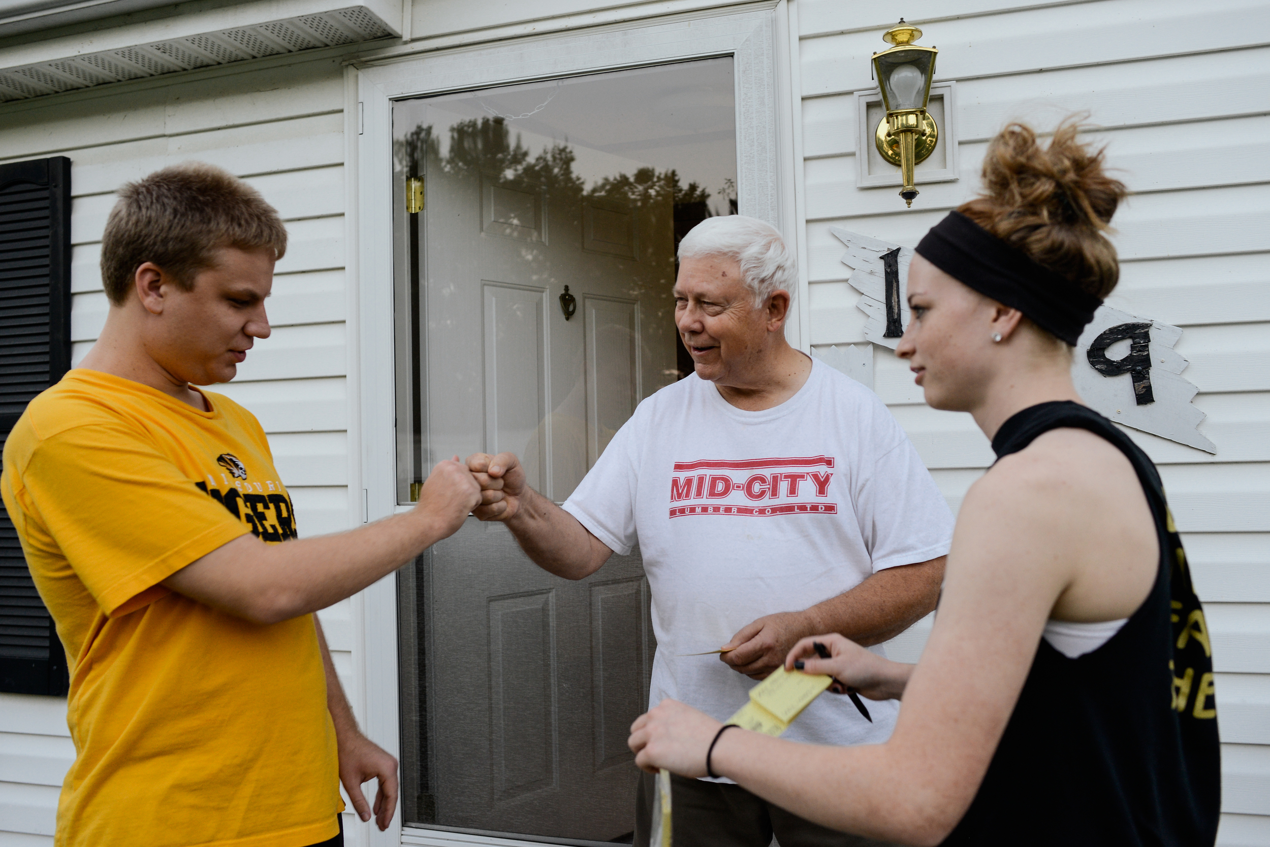  Trenton, Missouri. 2013.  A neighbor greets Dalton and his sister, Angela, as they sell raffle tickets. People in the community enjoy him stopping by. 