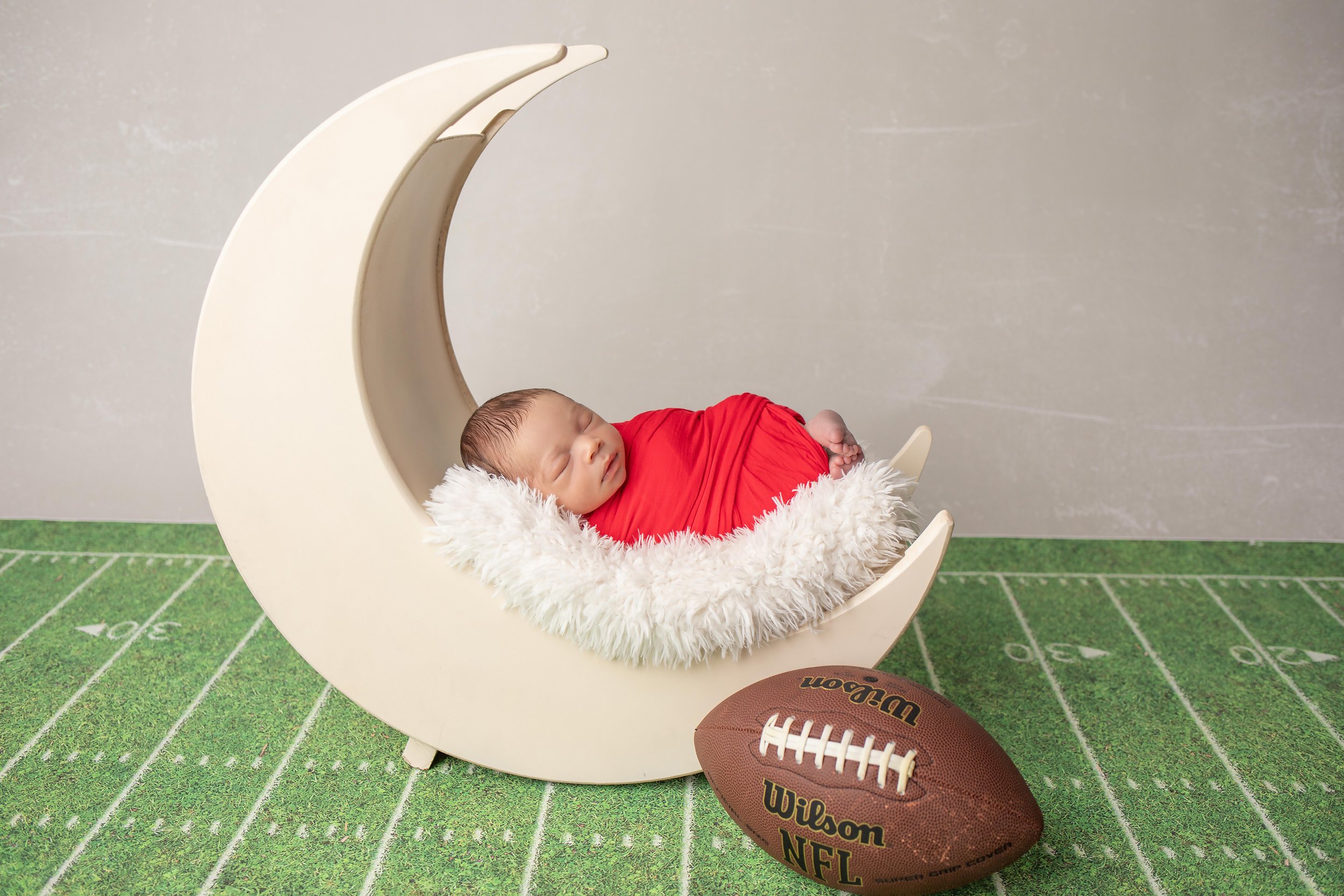 newborn photoshoot with football in matthews, nc