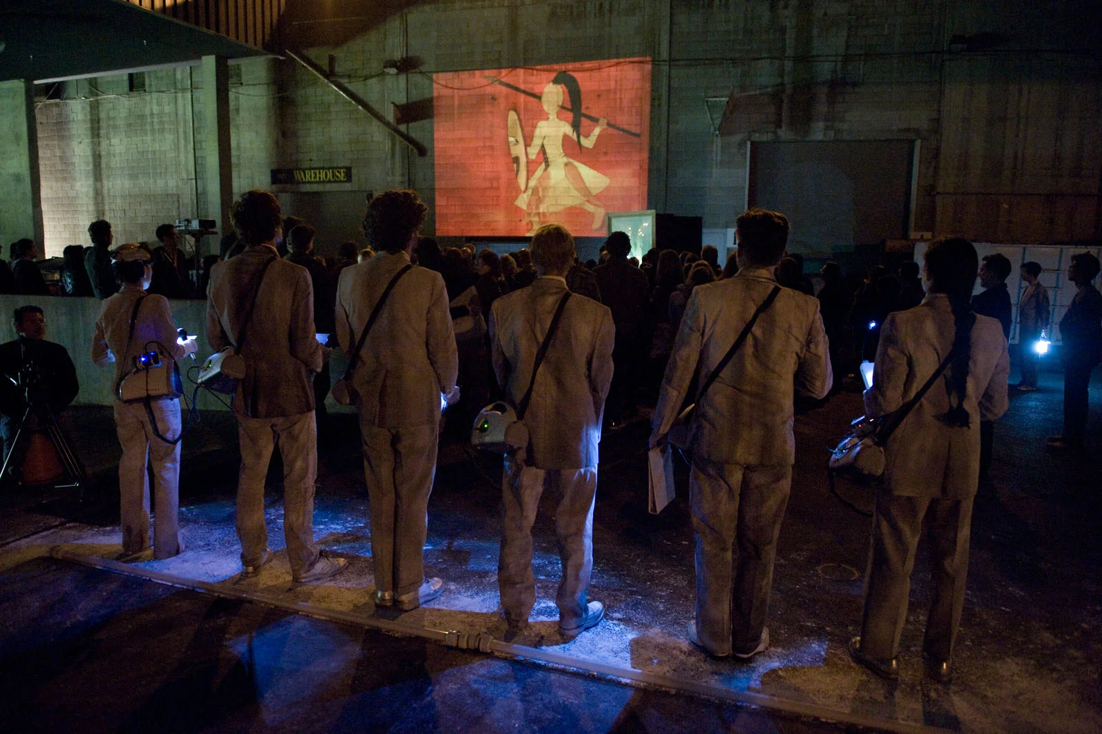 The singers look on as the animation appears on the concrete walls of Memorial Stadium