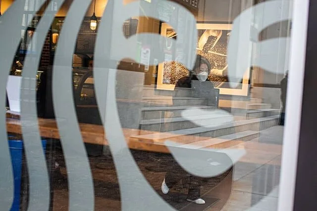 A person wearing a mask leaves an empty Starbucks on March 17th. Starbucks Canada has announced plans to reopen &quot;as many stores as possible&quot; by the end of May. Currently, open locations only accept orders via the company's app. Moving forwa