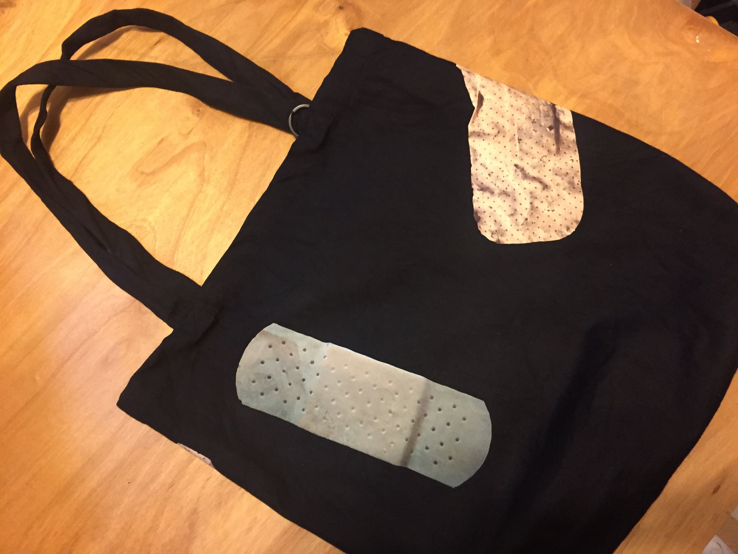 Bandage Tote, 15”x15”x4” Heavy 10oz 100% cotton. Pre-washed and Shrunk. 24” handles. Available in Black and Natural. Comes with a ring for key chain. Each Bandage Bag is unique.