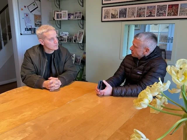  A closer 2-SHOT, to see the FRAMED FAMILY PHOTOS we’ll take during wardrobe fittings and place on the shelves behind DAD, and to see the looks of concern on the parents’ faces as they imagine what might happen if the money takes too long to get to J