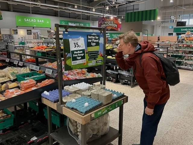  And here’s EGG MAN, at the PICK-YOUR-OWN EGG DISPLAY, where we see him reading a SIGN above the EGGS.  