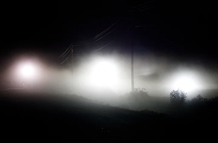  Dust is illuminated by race vehicle headlights in the middle of the desert race course.&nbsp; 