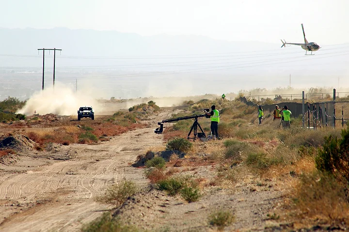  The Riot Racing truck kicks up a cloud of dust as it prepares to pass by its film crew and helicopter.&nbsp; 