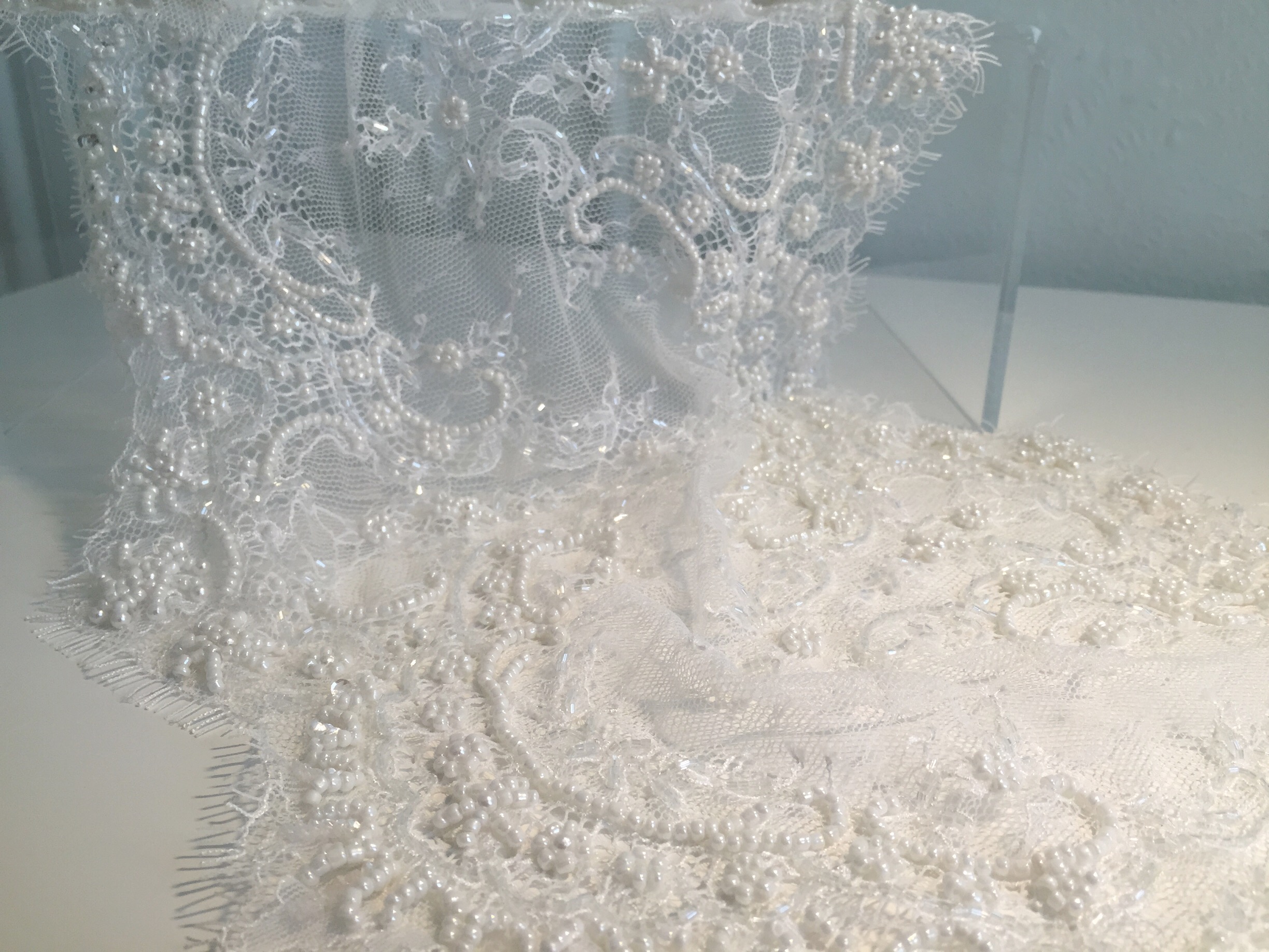 Beaded lace: A lot of chantilly and alençon laces may be beaded, particularly when it comes to bridal laces. Above is a beaded chantilly lace, with beads used to outline some of the floral motifs. This example also shows the eyelash fringe detail along the scalloped edge, which makes this a beautiful and elegant choice for a hem of train or if scallop depth allows, along a neckline and/or armhole of a bodice. When looking for beading lace, be sure to consider the additional time required to work with the fabric. 