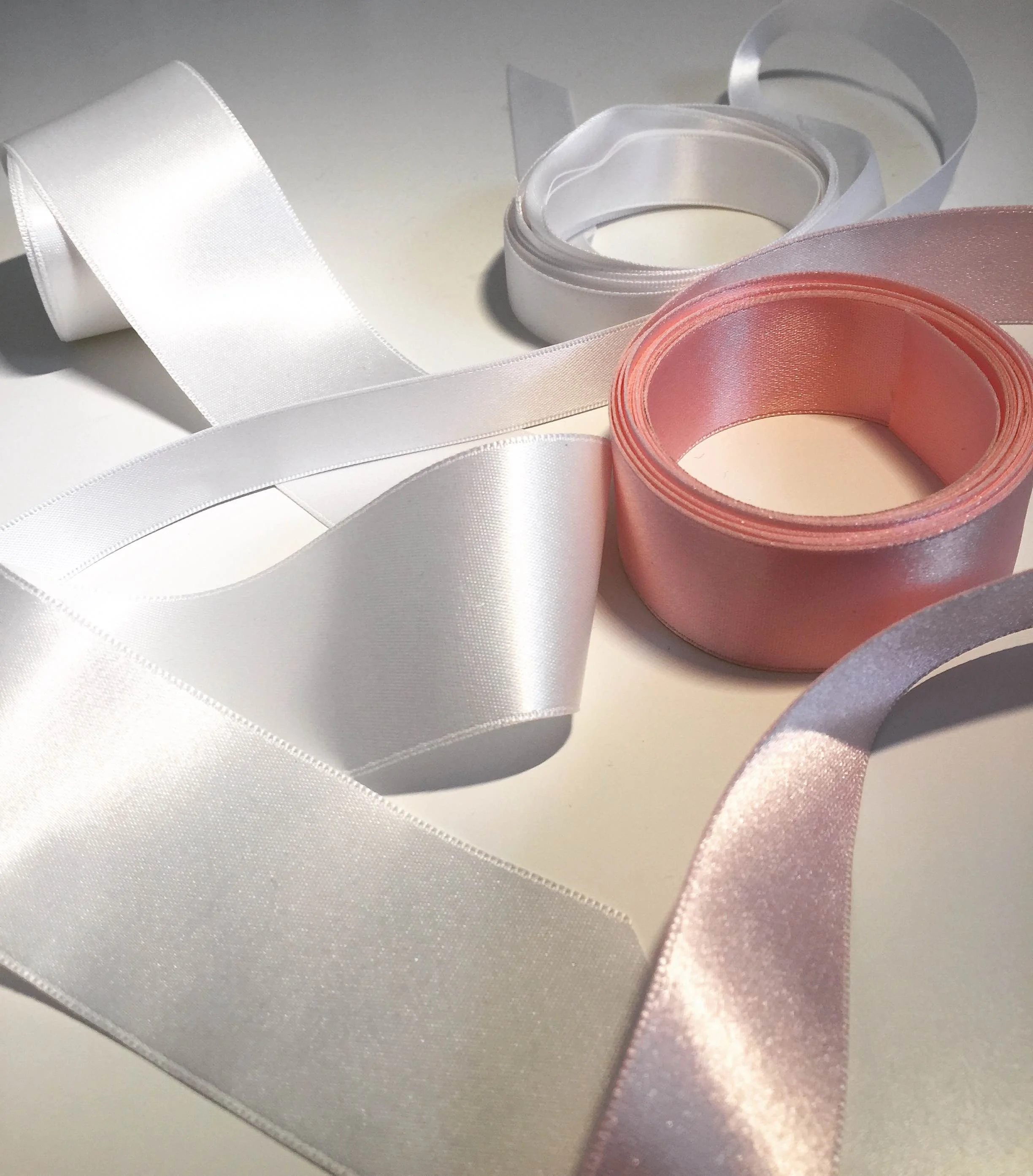 Satin Ribbon is probably the most commonly thought of trim when it comes to bridal belts and sashes. Available in a ton of colors and variety of standard widths, usually between 1/8th" to 3 or 4", these can also come in a variety of qualities. There are thin, paper-y, stiff varieties that work better on a hat or an Easter basket, but a good bridal satin trim to search for or ask for is a double-faced polyester satin trim. Pictured here are a few of these, which are shiny on both sides, and slightly thicker than a basic satin trim. Thickness is especially important if you have a lace dress with a texture that might show through as bumps under a thinner satin. Also consider the width of the ribbon compared to the waistline on your dress and your bust size. A very thin trim may be the best way to bring waist definition on delicate dress or for a bride with a larger bust, while a more substantial dress or a bride with a smaller bust may benefit from a 2" wide trim. Much bigger than 2" is often tricky, because the shape of a waist usually curves in and out at about 1" above and below. Keeping an extra wide trim in place may require seams or darts to contour properly. 
