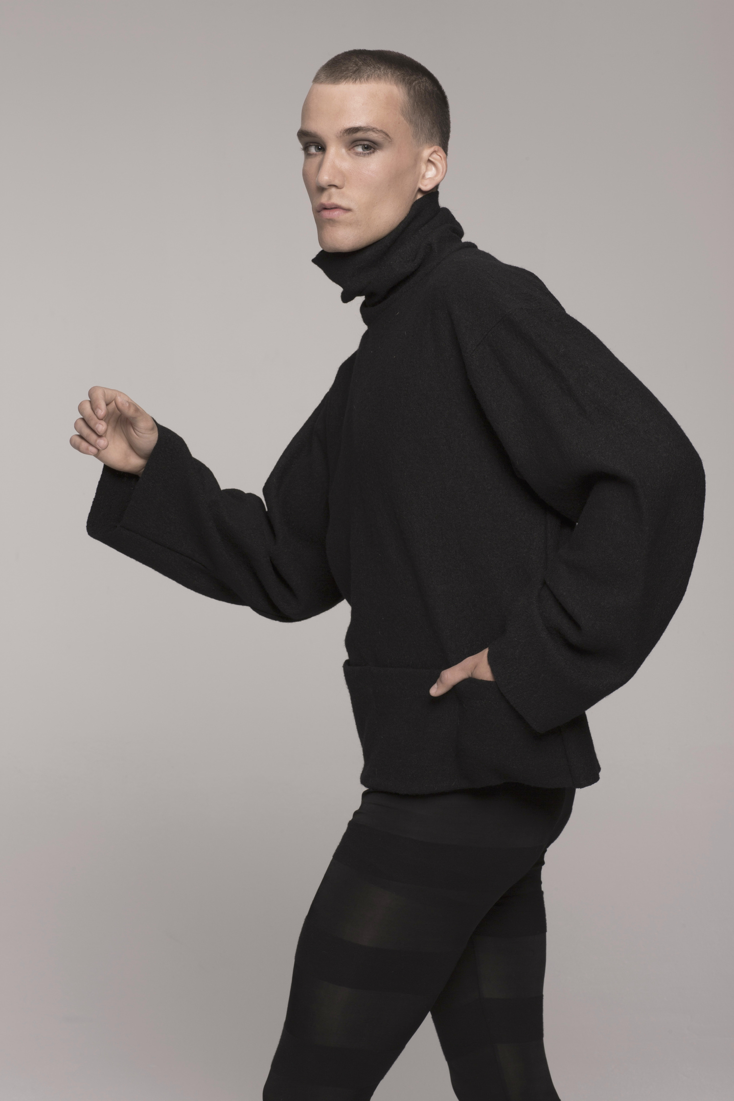 Male model, facing to side, hand in pocket, in black ONE-SIZE-FITS ALL UNISEX SWEATER