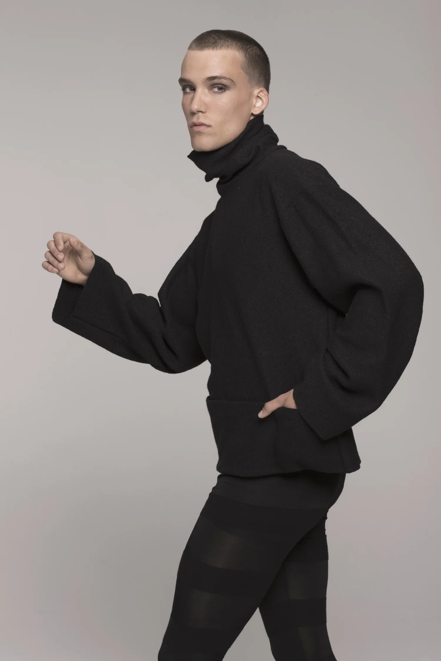 Male model, facing to side, hand in pocket, in black ONE-SIZE-FITS ALL UNISEX SWEATER