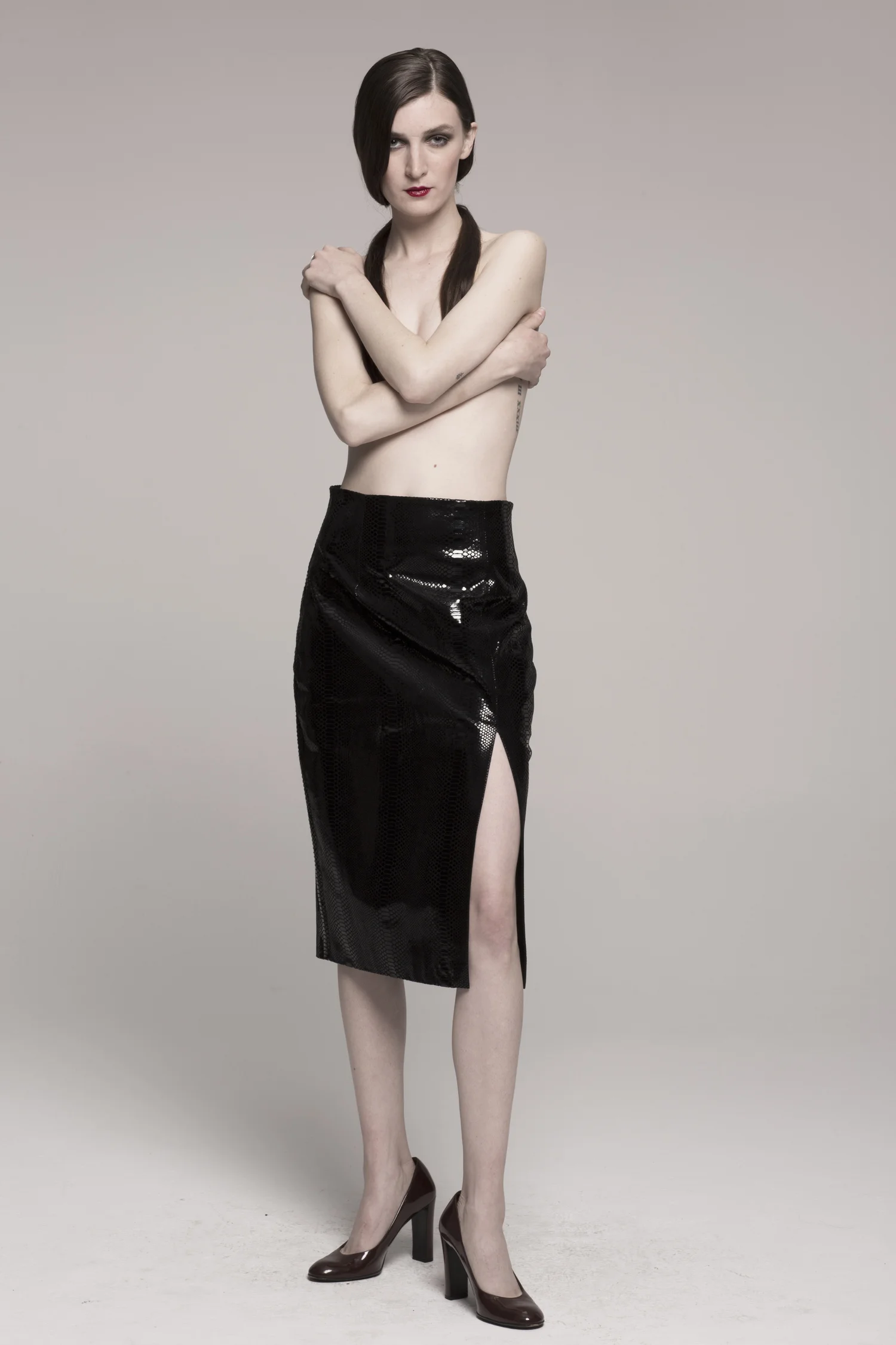 model in pencil skirt, arms across nude chest, facing camera