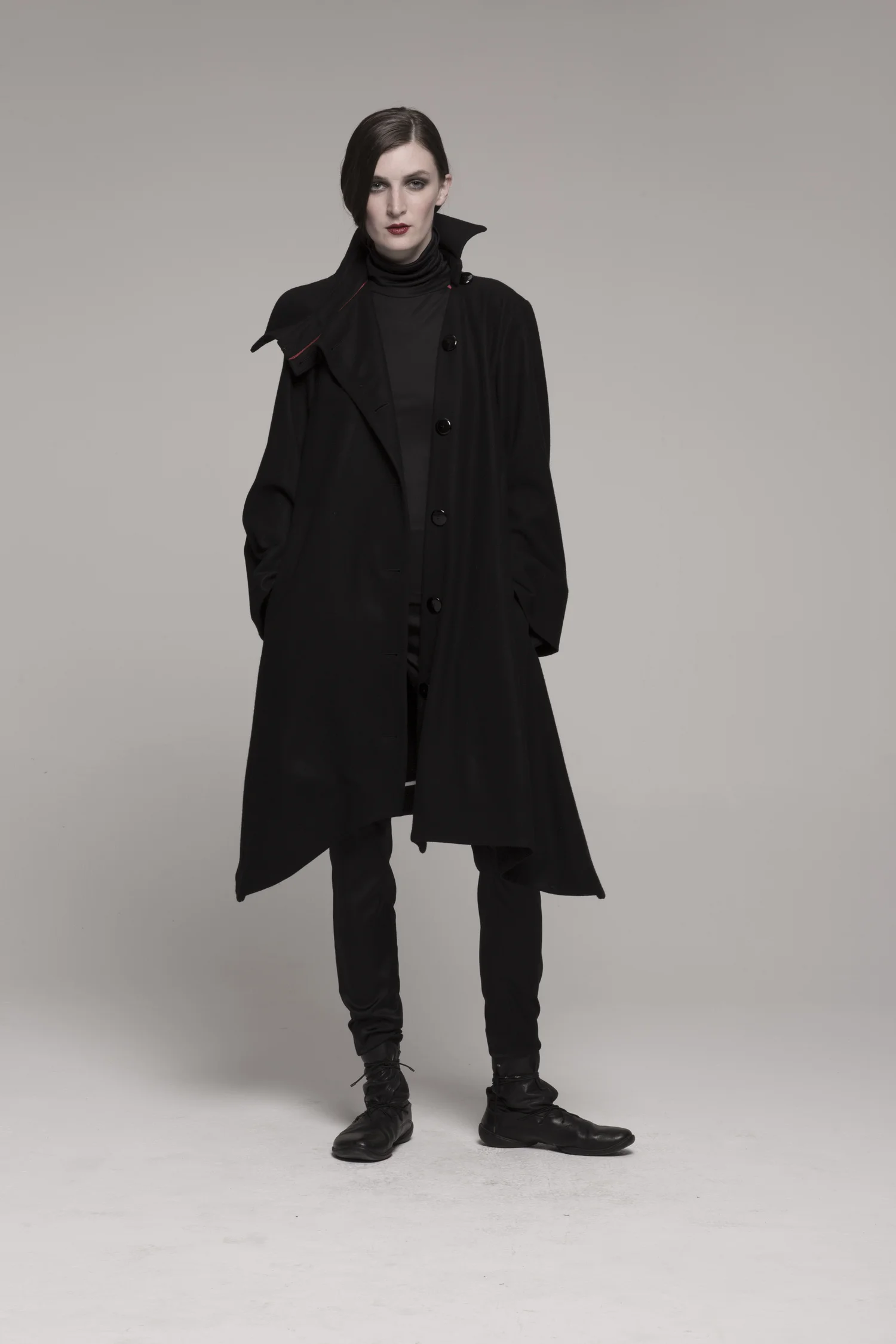 model in knee-length black coat with collar, hands in pockets