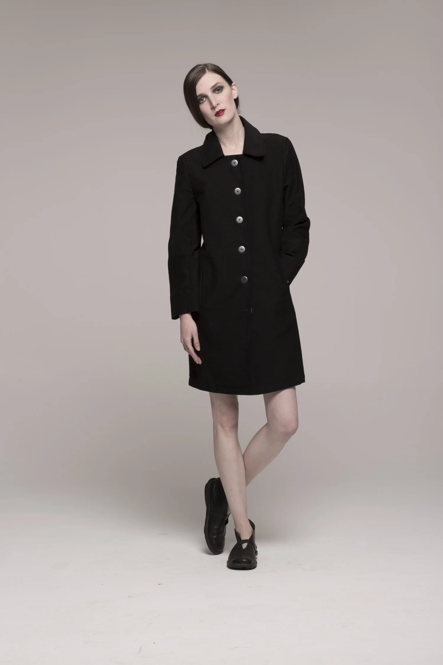 model in dark trench coat style dress, silver buttons