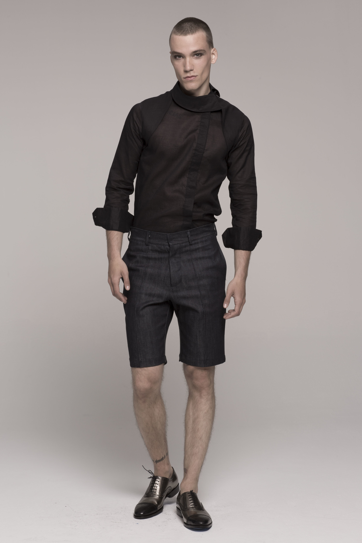 male model in sheer black shirt, sleeves rolled up, facing camera