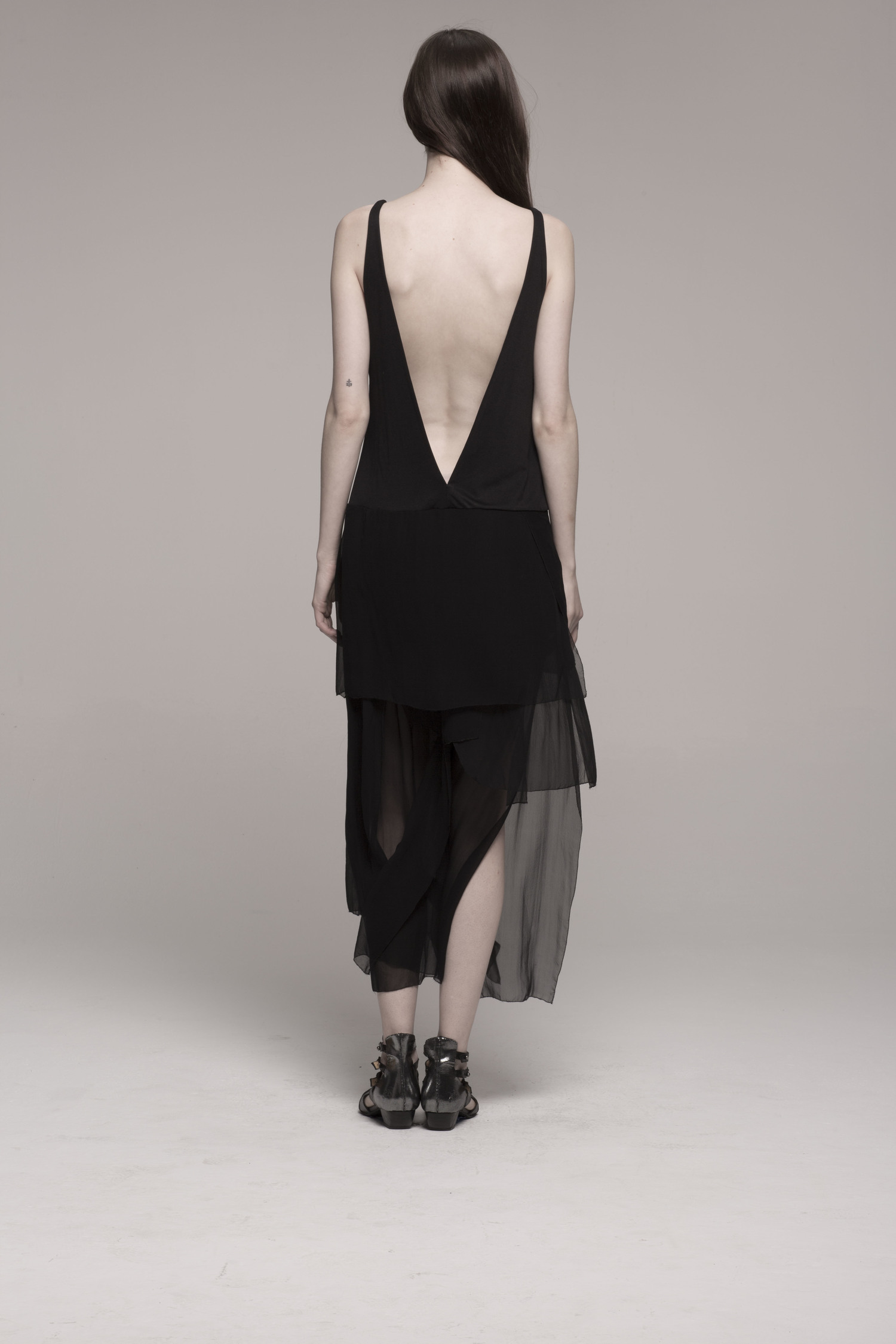 model in nude black dress with low back; back to camera