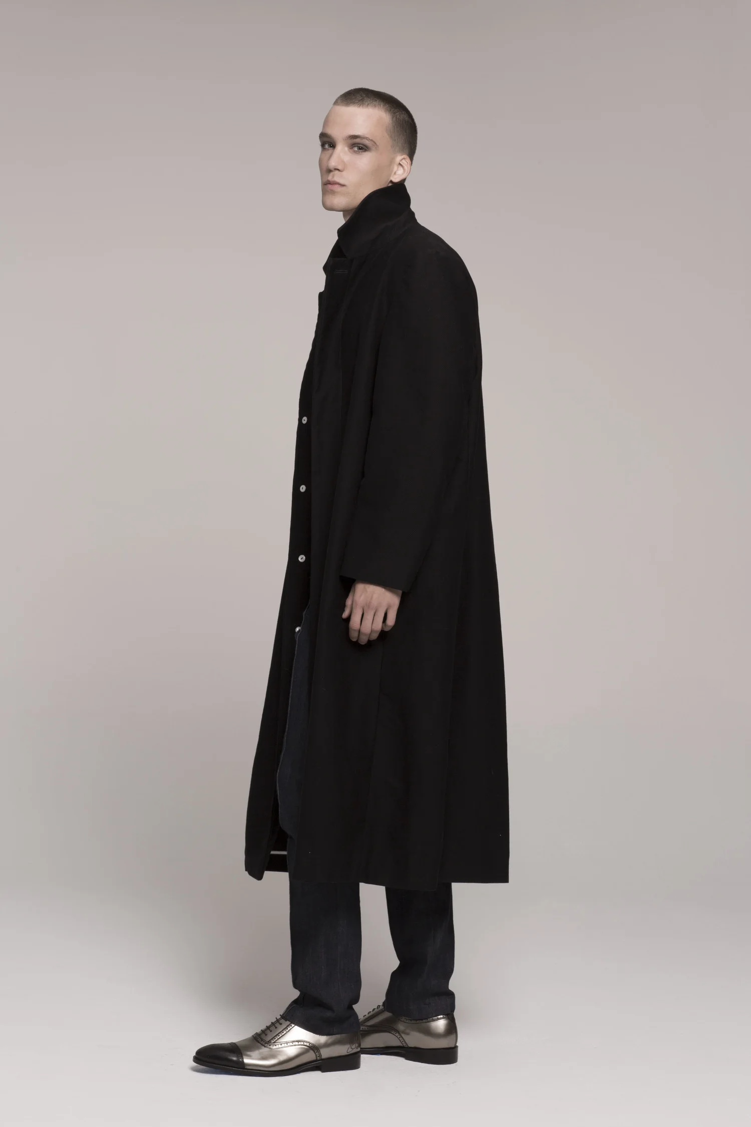 male model in long black coat, side view