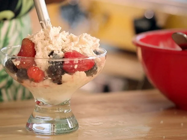 Créditos: GNT Ingredientes Frutas: 200g de morango 200g de amoras 200g de pitangas Chantily de coco: 400g de coco seco 2 copos de água quente 1 colher (sopa) de essência de baunilha 3 colheres (sopa) de açúcar de coco 1 garrafa de chantily (sifão) Modo de preparo Bata o coco seco com a agua quente no liquidificador. Passe por um saco vegetal ou uma peneira bem fina. Reserve o leite de coco. Coloque o leite de coco numa vasilha com tampa dentro da geladeira até endurecer (o ideal é ficar no mínimo 8 horas na geladeira). Quando o leite endurecer, a água vai descer e a gordura do coco ficará na parte superior da vasilha. Recolha essa gordura com a ajuda de uma colher e leve para uma outra tigela. Nessa tigela, adicione o açúcar de coco e a essência de baunilha e misture bem. Ponha a mistura de coco dentro da garrafa de chantily. Sirva o chantily com as frutas já higienizadas dentro das taças. Bom apetite. Confirma mais receitas no livro Bela Cozinha 2 . 