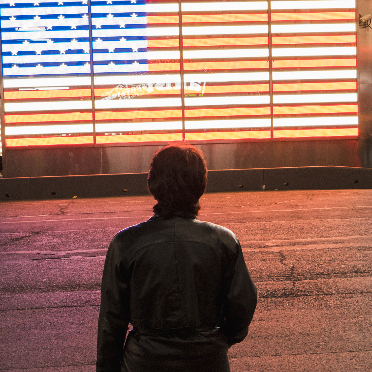 A woman in a black leather jacket looking at an american flag ma