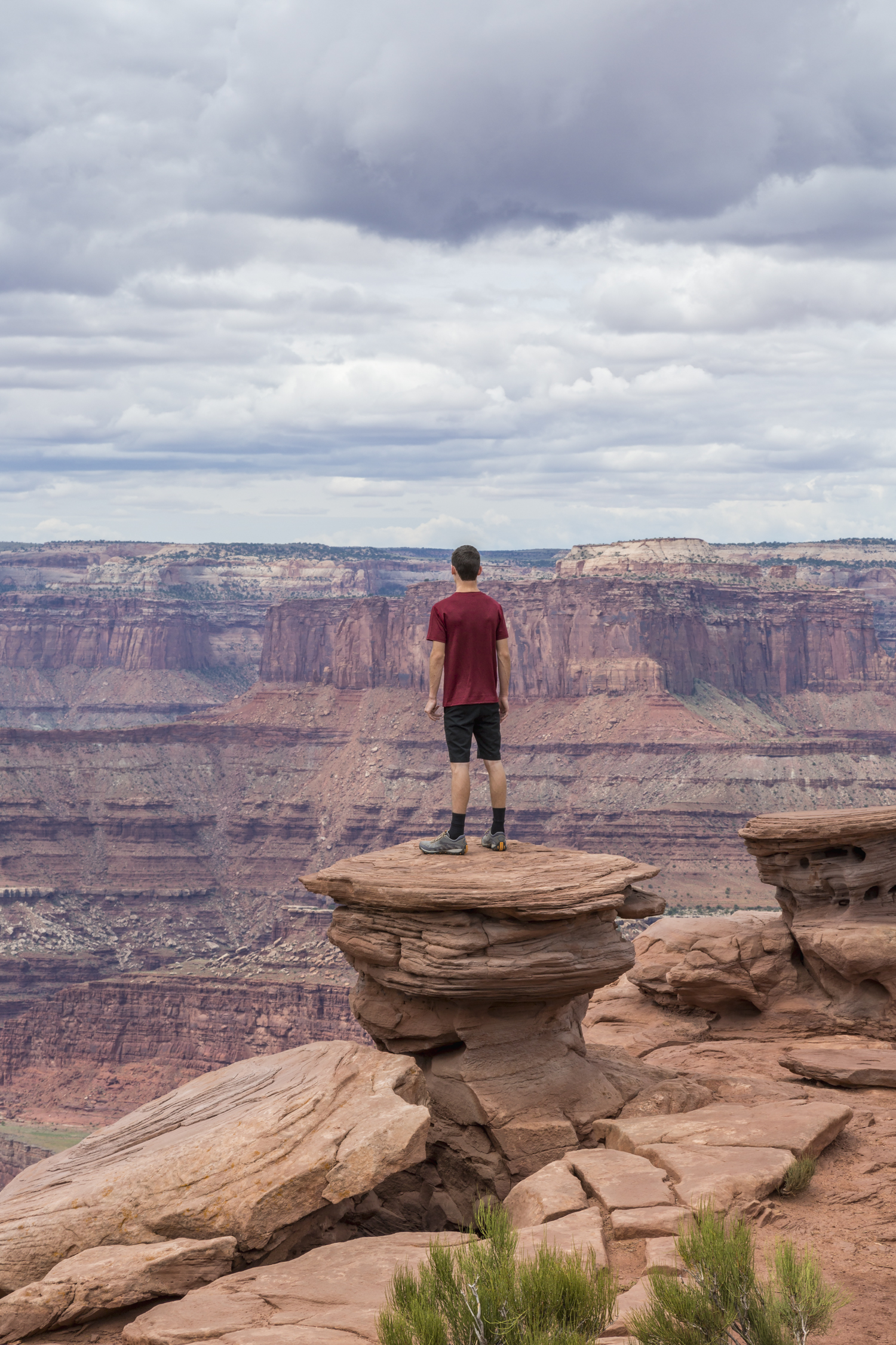 Teenage boy standing a rock pillar looking out over a vast lands