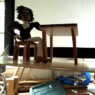 Gregory, the main character, seated in front of the shadow screen. Visible beneath the deck (and running through the legs of the table) are the controls for his left hand