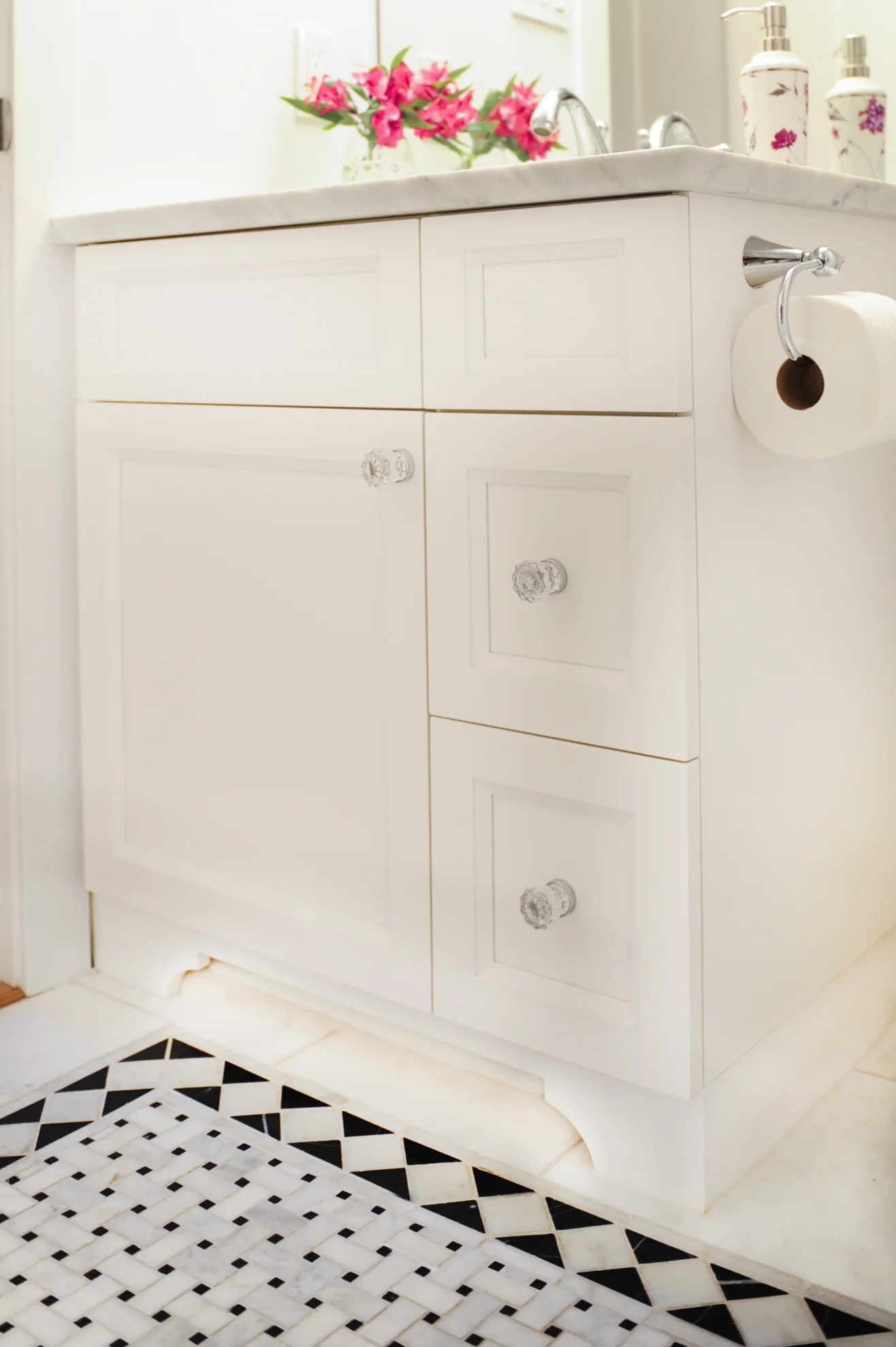 A custom vanity with crystal pulls and a marble countertop presides over a stunning mosaic floor.