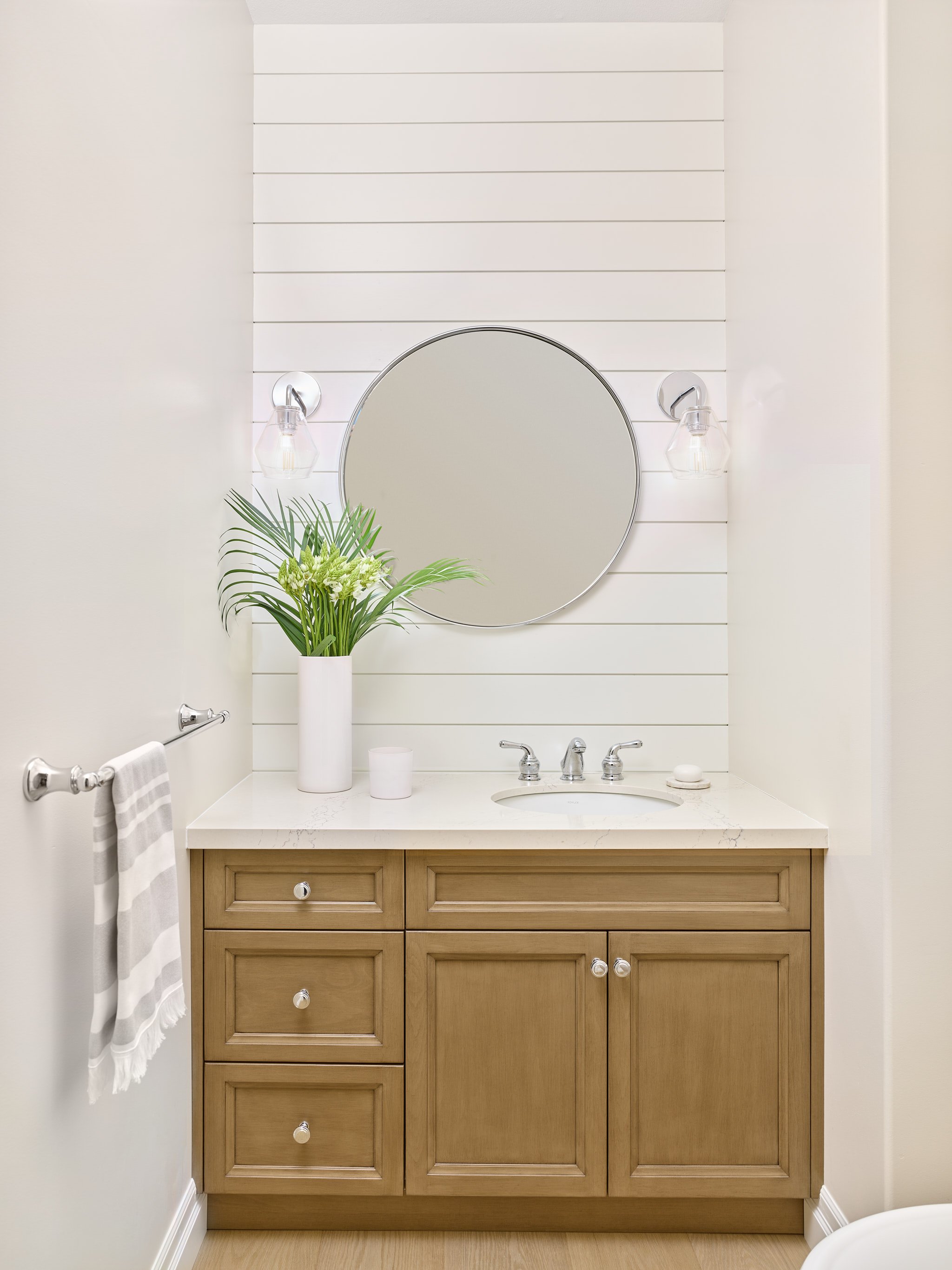 Formerly burgundy, this powder room now sports a crisp, white palette where shiplap provides interest and a custom vanity adds warmth.