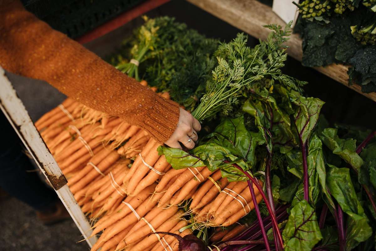 Photo credit: Mason Trinca for the San Francisco Chronicle . Kendra Aronson grabs a bunch of carrots at one of her favorite booths, Domingo Farms in Arroyo Grande, at the Farmers Market in San Luis Obispo.