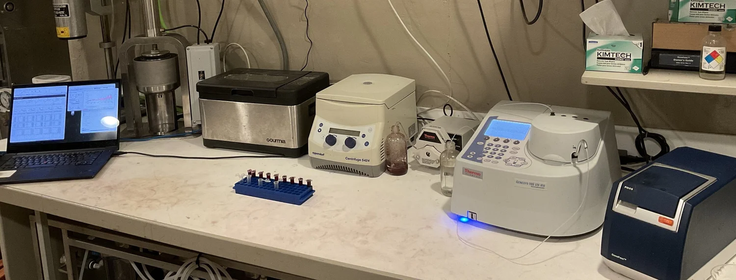 The dry lab bench: laptop, two centrifuges, a rack of sample vials, a benchtop spectrometer and a printer
