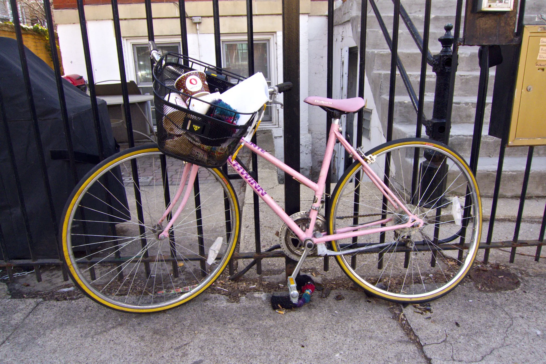 A sad bicycle leans, locked against a fence on Sheffield Ave. just north of Armitage Ave. 