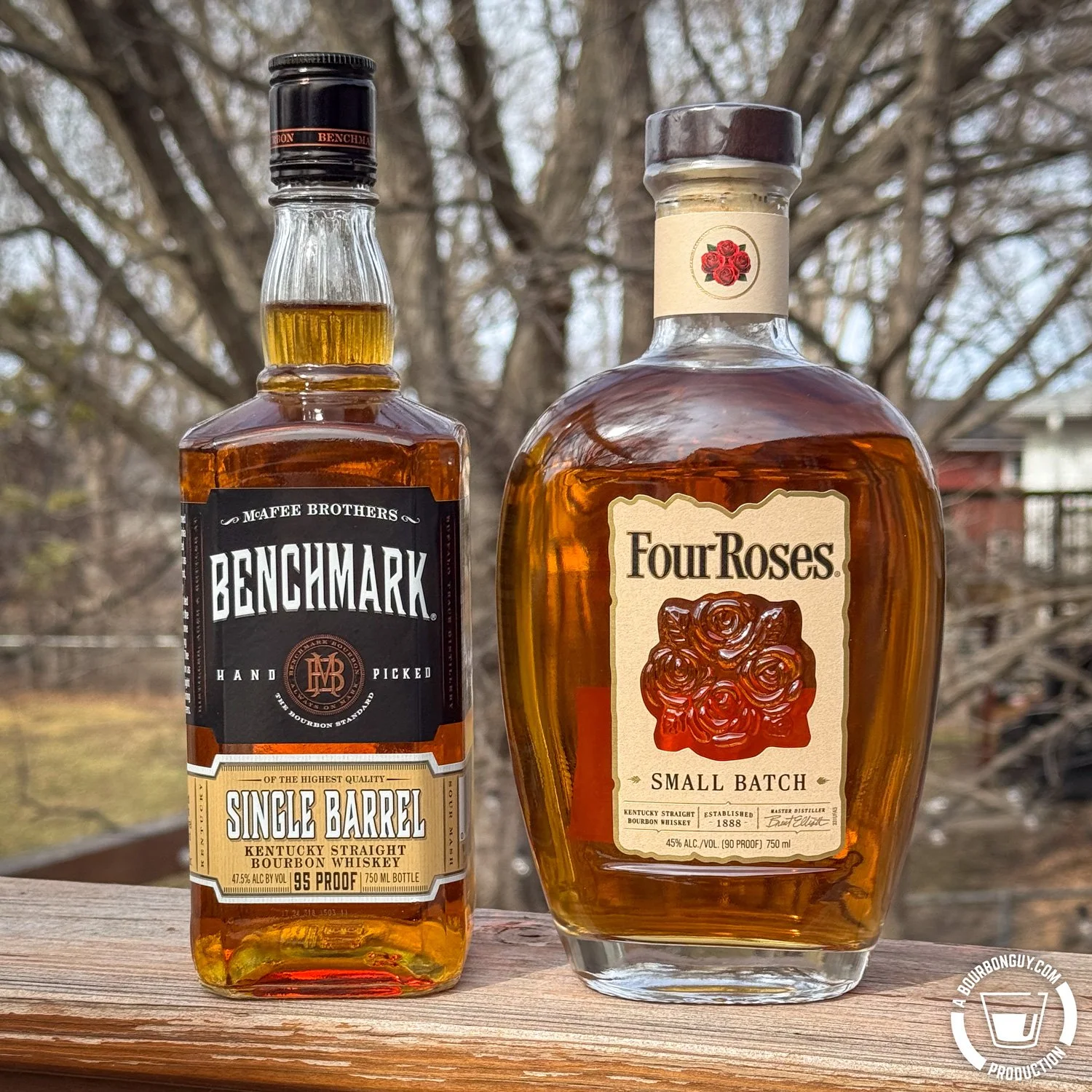 IMAGE: Benchmark Single Barrel and Four Roses Small Batch bourbon bottles side by side on a deck with trees in the background