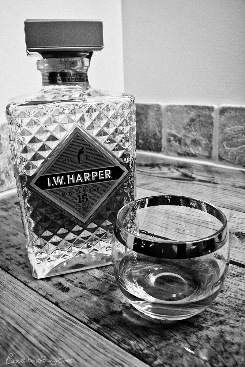 IW Harper 15 year old bourbon in decanter shaped bottle. A glass of bourbon on the side.