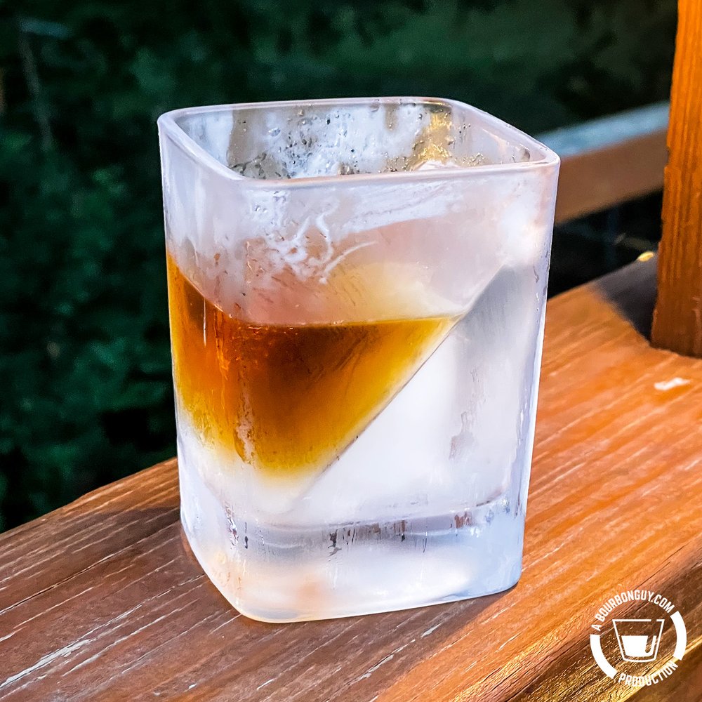 IMAGE: A frosty glass of whiskey fresh from the freezer. The ice cube is frozen into the glass in a wedge shape.